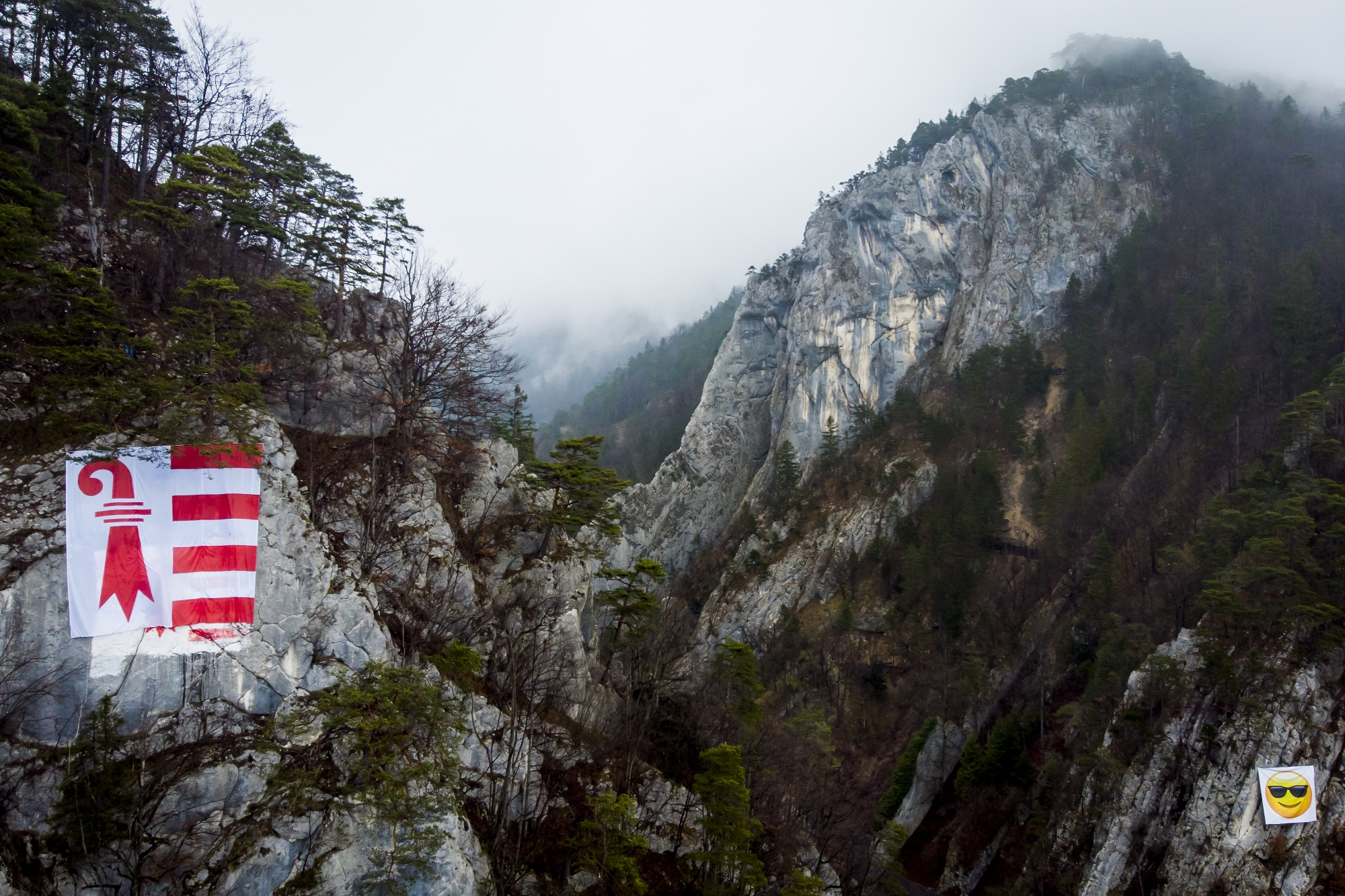 Un drapeau du canton du Jura du comite "Moutier ville jurassienne" est visible a cote d'une banderole du mouvement antiseparatiste "Moutier Plus" dans le cadre de la campagne sur la votation a l'entree des gorges le vendredi 5 mars 2021 a Moutier. Le 28 mars prochain, les Prevotois doivent revoter sur l'appartenance cantonale de la ville de Moutier, apres l'annulation du scrutin du 18 juin 2017. Les autorites du canton de Berne et du Jura se sont engagees a ne pas faire campagne activement dans le cadre du vote sur la Question jurassienne. (KEYSTONE/Jean-Christophe Bott)