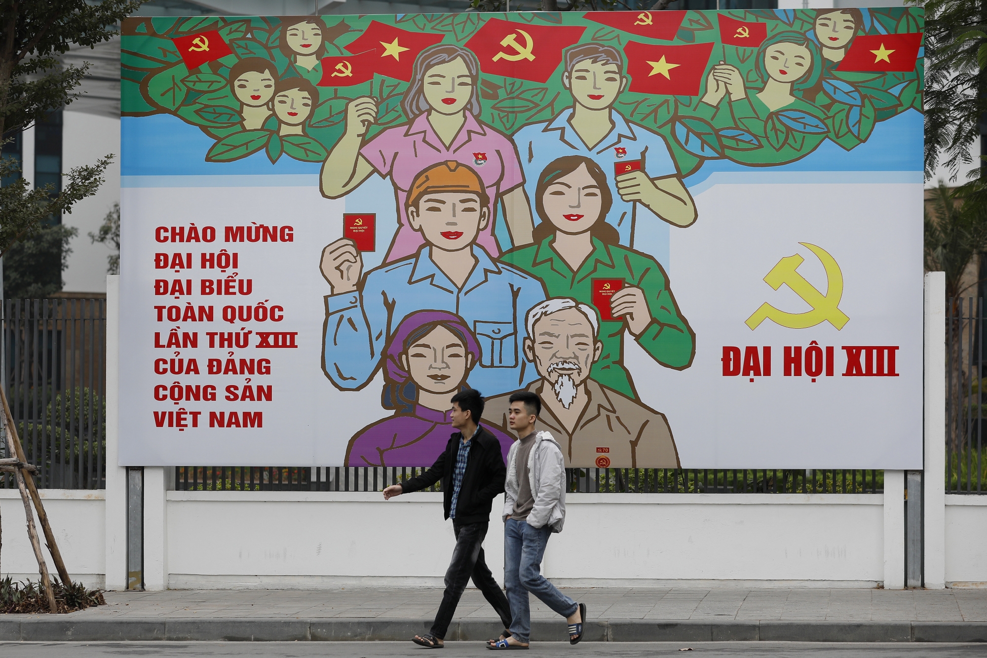 epa08963565 Two men walk past a billboard for the 13th National Congress of Vietnam's Communist Party (VCP), in Hanoi, Vietnam, 25 January 2021. The VCP's 13th congress, which runs from 25 January through 02 February at the National Convention Center in Hanoi, will choose the party's new leadership. EPA/LUONG THAI LINH