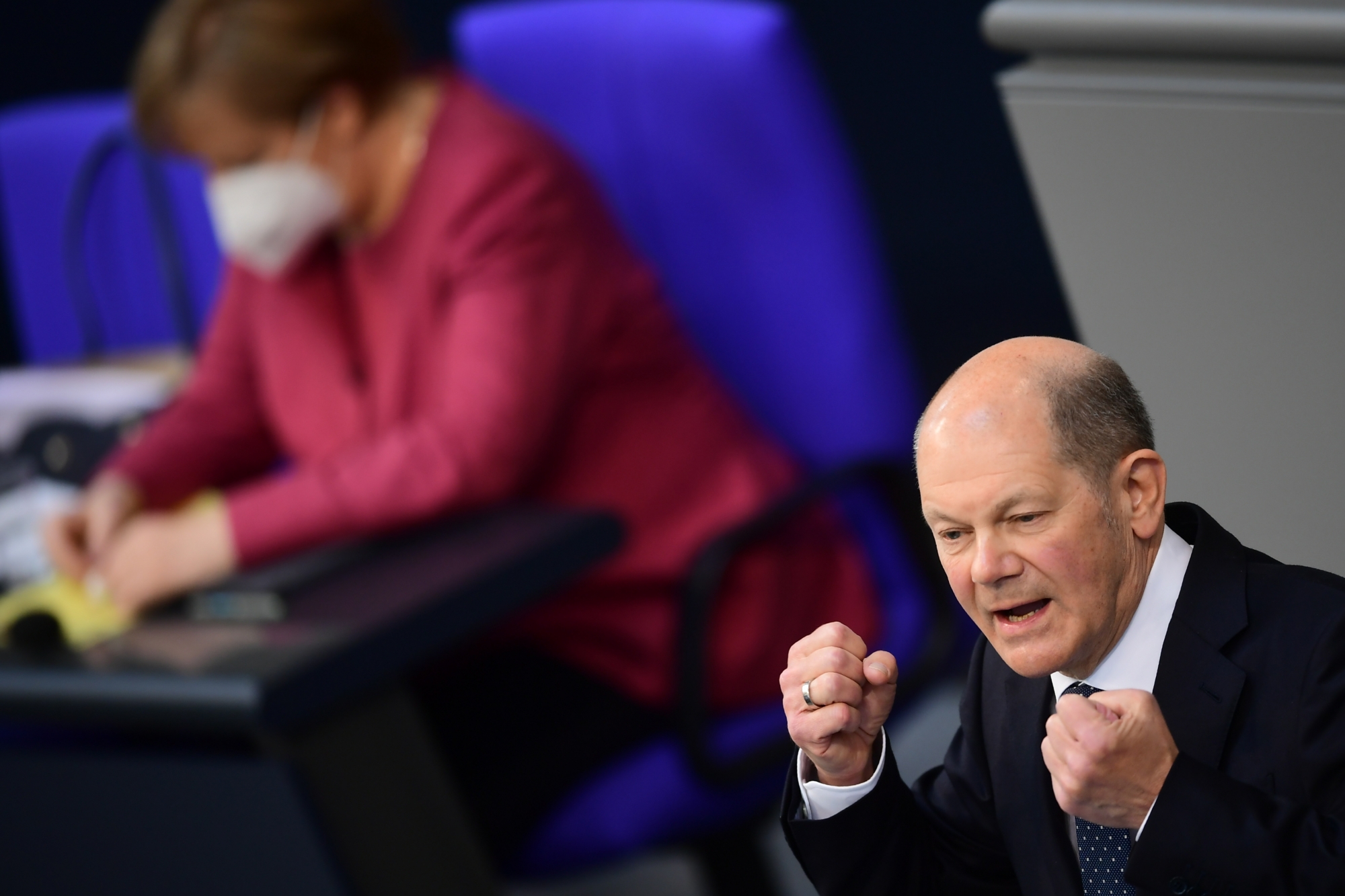 epa09149259 German Minister of Finance Olaf Scholz speaks next to German Chancellor Angela Merkel during a session of the German parliament Bundestag in Berlin, Germany, 21 April 2021. The German parliament consults about a change of the Protection against Infection Act (Infektionsschutzgesetz). With the changes discussed, the federal government shall be granted with more power regarding the enforcement of Coronavirus measures in the federal states. EPA/CLEMENS BILAN