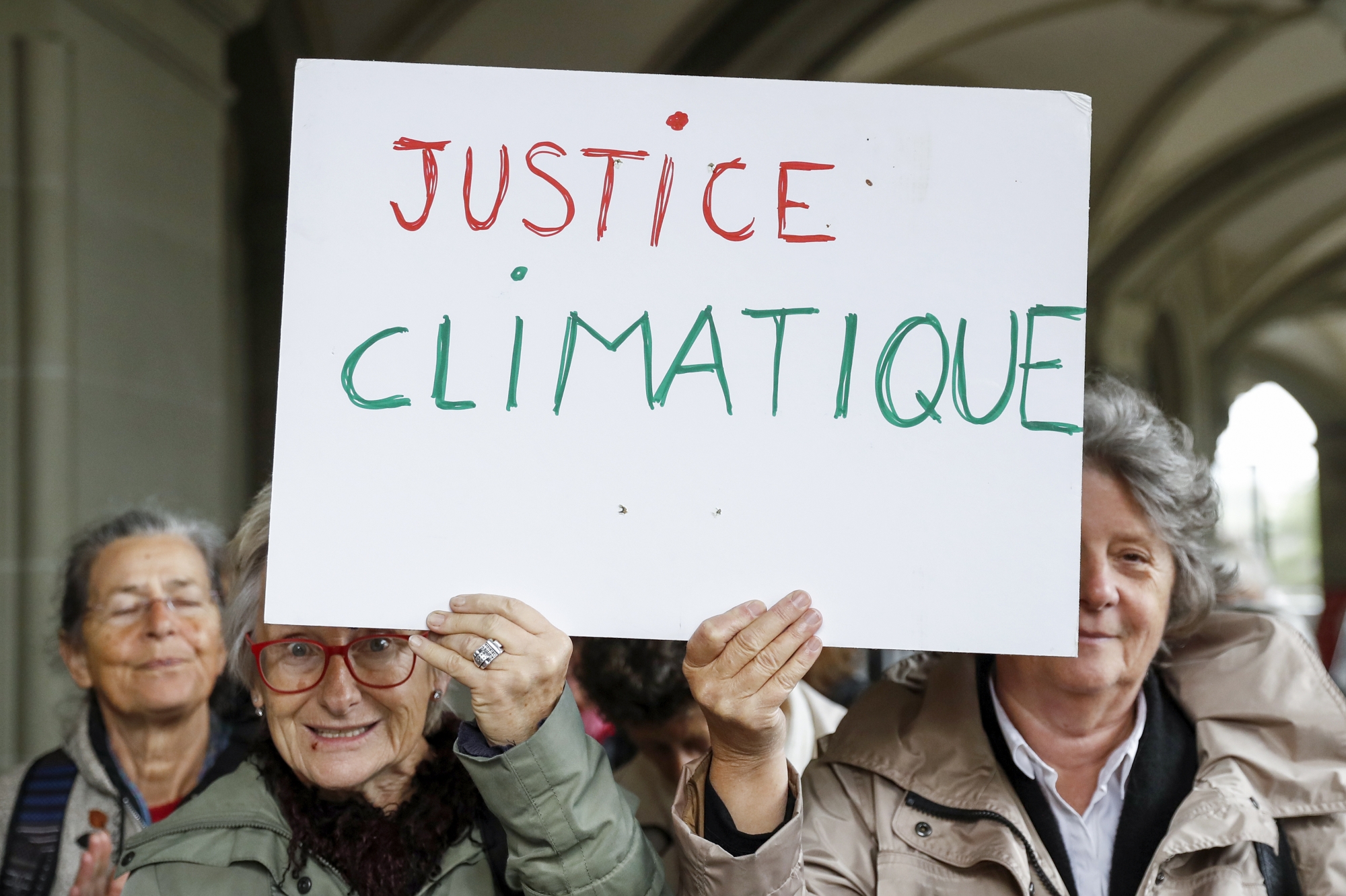Seniorinnen halten eine Tafel mit der Aufschrift "Justice Climatique" hoch, nach einer Medienkonferenz des Vereins KlimaSeniorinnen, am Dienstag, 25. Oktober 2016 in Bern. Der Verein verlangt eine Korrektur der schweizerischen Klimapolitik und reicht eine Klage beim Bund ein. (KEYSTONE/Peter Klaunzer)