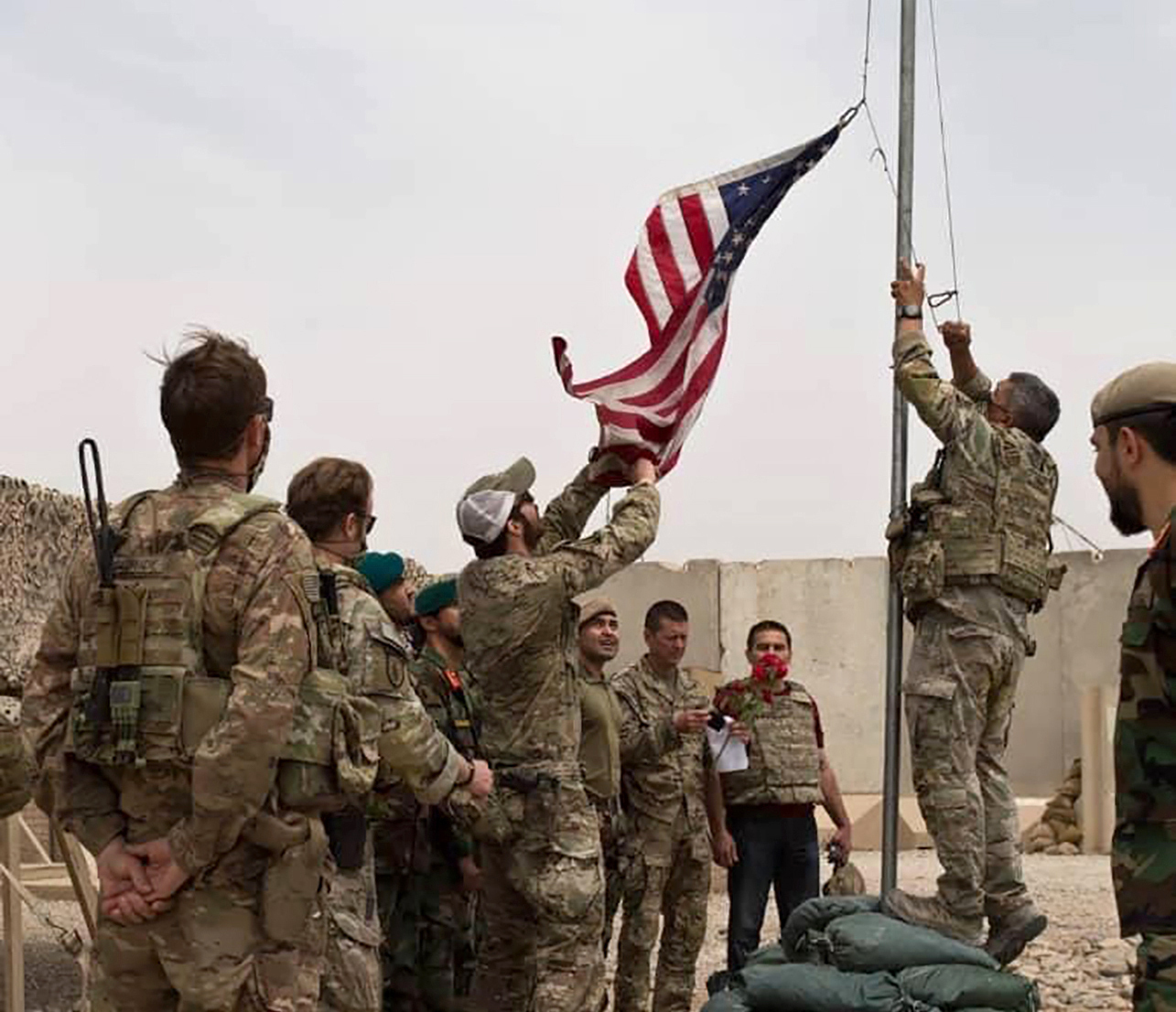 A U.S. flag is lowered as American and Afghan soldiers attend a handover ceremony from the U.S. Army to the Afghan National Army, at Camp Anthonic, in Helmand province, southern Afghanistan, Sunday, May 2, 2021. (Afghan Ministry of Defense Press Office via AP)