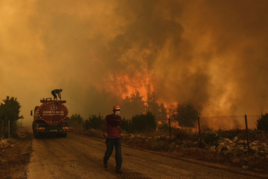 Un homme descend une route dans le village de Sirtkoy ravagé par le feu, près de Manavgat, en Turquie. Plus de 100 incendies de forêt ont été maîtrisés en Turquie, selon les autorités.