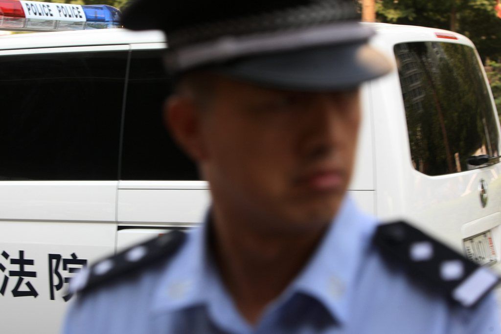 epa03833095 A Chinese police officer stands guard while a police vehicle which is believed to be transporting Bo Xilaiarrives at Jinan Intermediate People's Court where China's former regional leader Bo Xilai is being tried, in Jinan city, China's Shandong province, 22 August 2013. Bo Xilai stands open trial at this court for charges of bribery, graft and abuse of power.  EPA/NG HONG