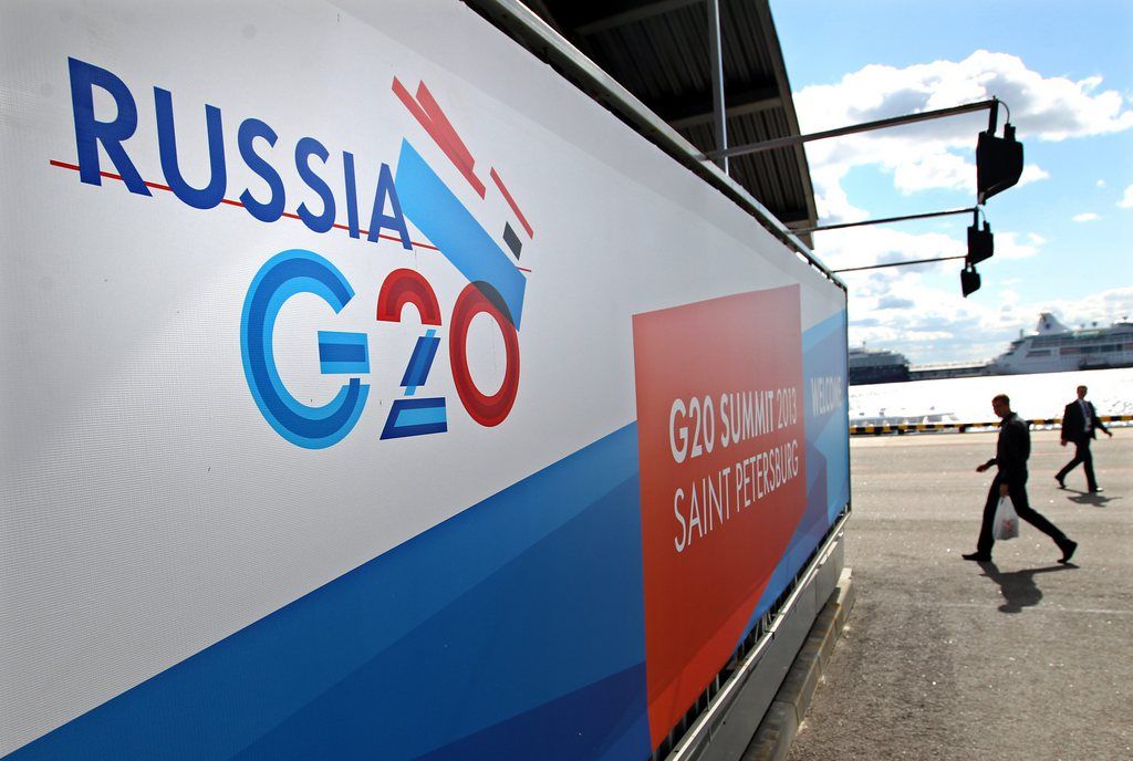 epa03849186 People walk past a banner for the G20 Summit at a port on the bank of the Neva River in St. Petersburg, Russia, 03 September 2013. The G20 Summit takes place from 05 to 06 September 2013 in St. Petersburg.  EPA/TATYANA ZENKOVICH