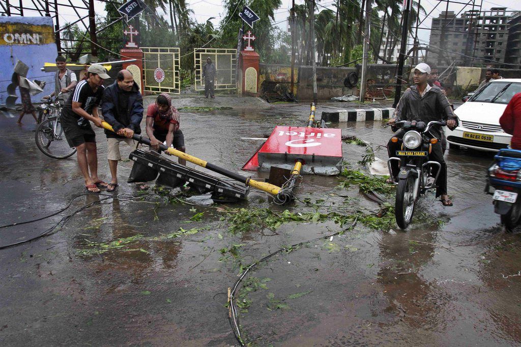 Des habitants du village de Behrampur enlève le pylône de feux de signalisation tombé pendant le passage du cyclone.  