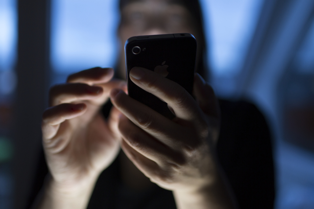 Eine Frau twittert zuhause in Zuerich ueber ihr iPhone, aufgenommen am 17. Mai 2013. (KEYSTONE/Gaetan Bally)