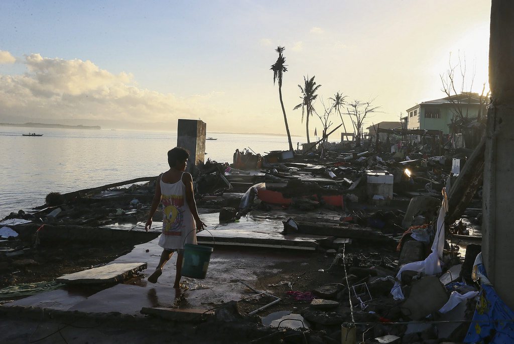 epa03950399 A Filipino woman carries water in the devastated city of Tacloban, Leyte province, the Philippines, 15 November 2013. Aid workers and relief supplies were being poured into eastern provinces hit by Typhoon Haiyan, which aid agencies and officials estimated has left thousands dead and staggering destruction in its wake.  EPA/NIC BOTHMA