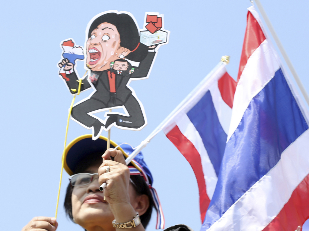 A Thai anti-government protester holds a cut board of Prime Minister Yingluck Shinawatra during a rally at Victory Monument in Bangkok, Thailand Sunday, Dec. 22, 2013. Thailand's main opposition Democrat Party said it would boycott February's general election, deepening a political crisis as protesters called for another major rally Sunday to step up efforts to oust the government and force political reforms. (AP Photo/Apichart Weerrawong)