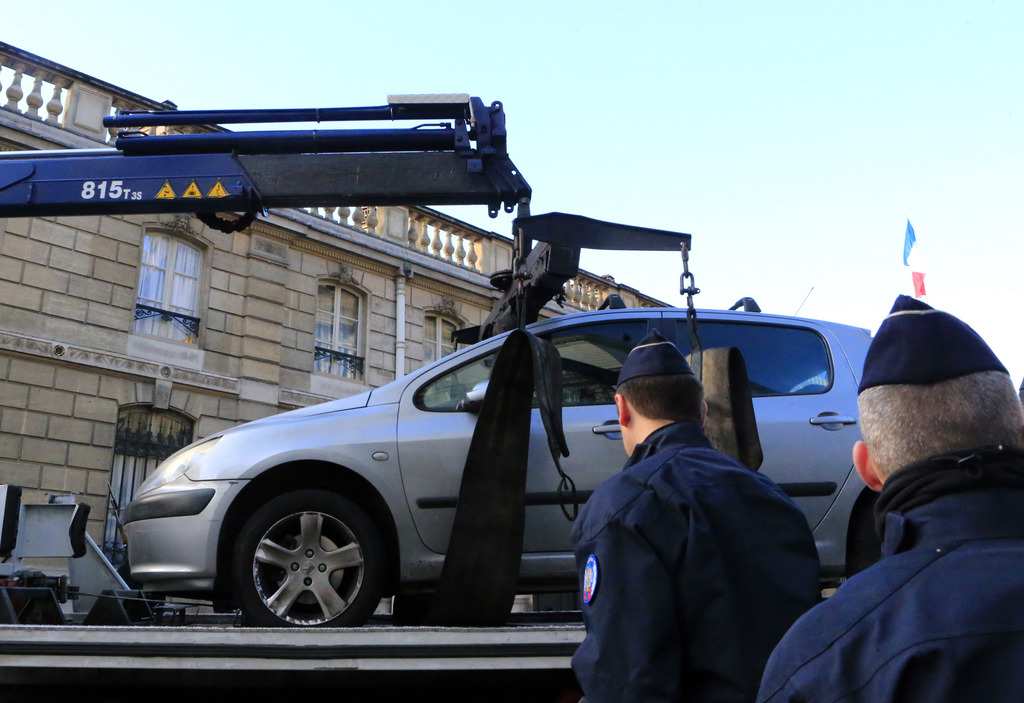 A car is towed away after an unidentified driver tried to ram through a gate of the presidential Elysee Palace, visible in background, Paris, Thursday, Dec. 26, 2013. An official, who is not authorized to be publicly named because of government policy, says the driver was stopped, and no one was hurt in the incident. An investigation is under way. (AP Photo/Jacques Brinon)