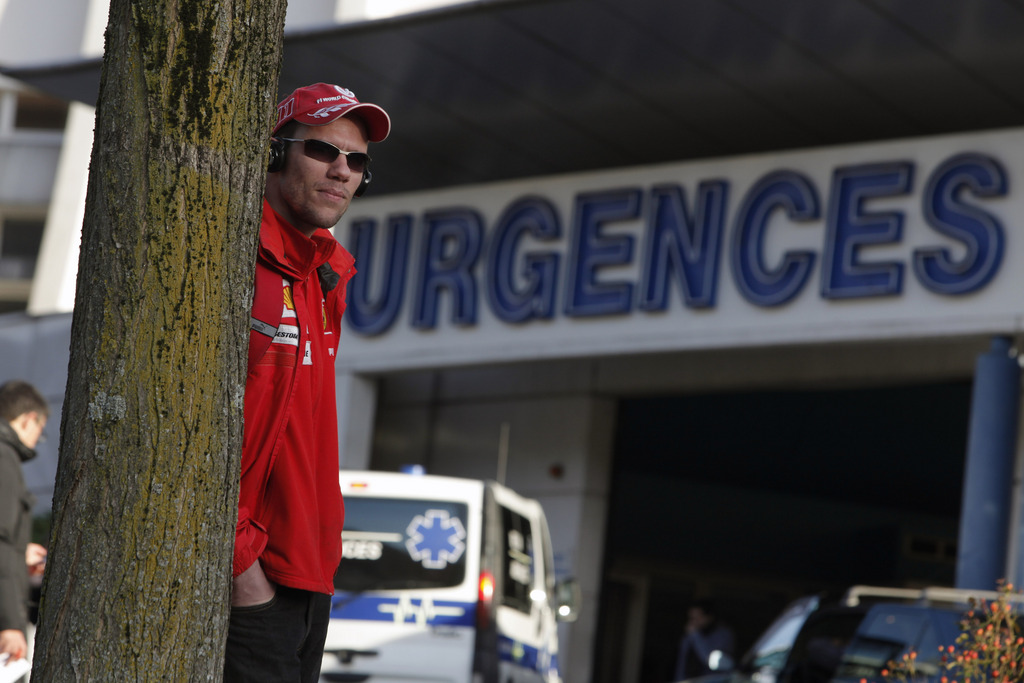 A Scuderia Ferrari fan waits in front of the Grenoble hospital, in the French Alps, where former seven-time Formula One champion Michael Schumacher is being treated after sustaining a head injury during a ski accident, in Grenoble, France, Monday, Dec. 30, 2013. Doctors treating Michael Schumacher refused Monday to predict an outcome for the seven-time Formula One champion, saying they were taking his critical head injury "hour by hour" following a skiing accident. (AP Photo/Thibault Camus)