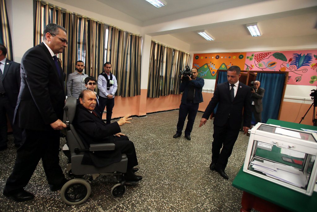 epa04169936 Algerian President Abdelaziz Bouteflika (L, on wheelchair), who is seeking a fourth term, arrives at a polling station in Algiers, Algeria, 17 April 2014. Bouteflika arrived in a wheelchair at a school in the capital where he cast his ballot. The 77-year-old incumbent, who has uttered only a few sentences in public since suffering a stroke last year, was accompanied to the polling station by his brother Said, who acts as his special adviser.  EPA/MOHAMED MESSARA