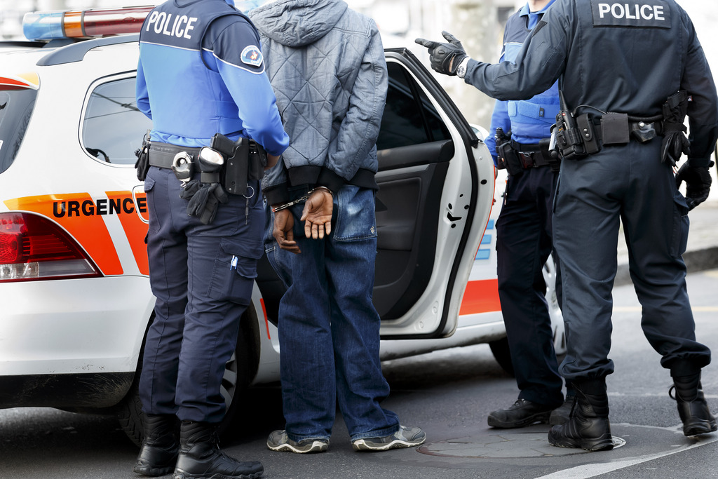 Des gendarmes de la police genevoise embarquent une personne menotte aux poings apr?s l'avoir arrete suite a un controle, ce mardi 25 mars 2014 a Geneve. (KEYSTONE/Salvatore Di Nolfi)