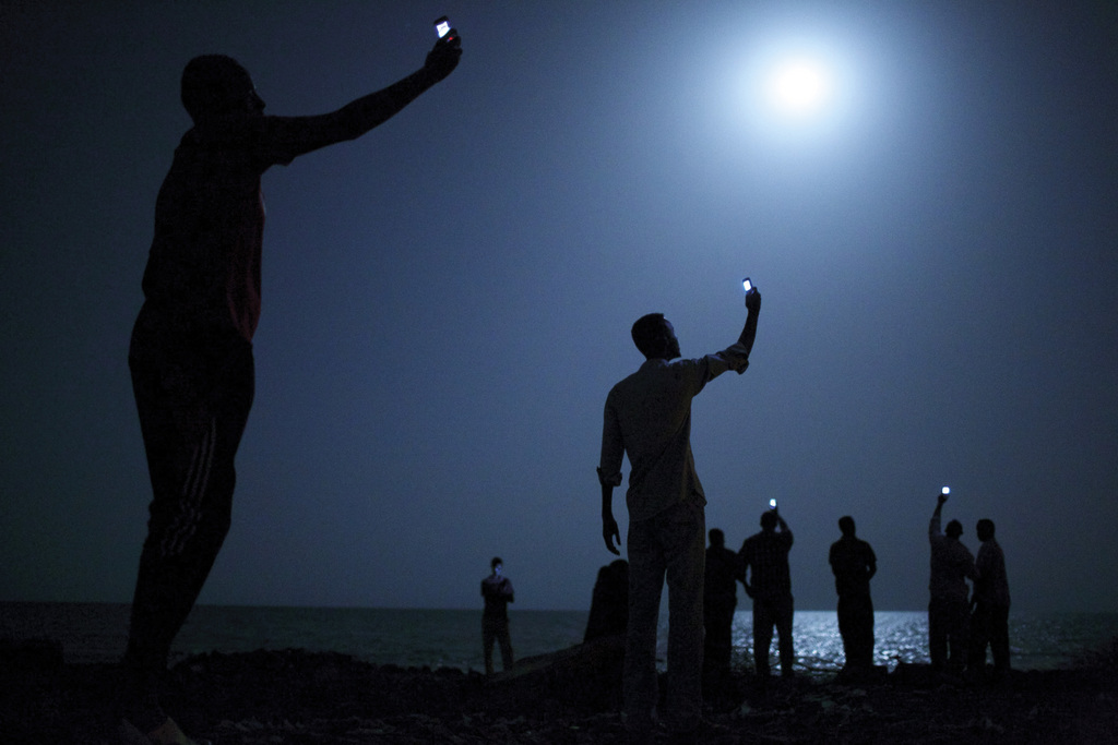 In this photo provided on Friday Feb. 14, 2014 by World Press Photo, the World Press Photo of the Year 2013 by John Stanmeyer, USA, VII for National Geographic, shows African migrants on the shore of Djibouti city at night, raising their phones in an attempt to capture an inexpensive signal from neighboring Somalia in Djibouti City, Djibouti, Feb. 26, 2013. (John Stanmeyer/VII for National Geographic).  NO SALES, THIS MATERIAL IS FOR SINGLE USE PUBLICATIONS IN PRINT OR FOR A TEMPORARY ONLINE PUBLICATION, AND MAY BE USED EXCLUSIVELY TO PUBLICIZE THE 2014 WORLD PRESS CONTEST AND EXHIBITION. IT MAY NOT BE PUBLISHED AS PART OF AN ARTICLE OR ANY OTHER ITEM THAT CONTAINS NO DIRECT LINK TO WORLD PRESS PHOTO AND ITS ACTIVITIES. THE PICTURE MAY NOT BE CROPPED OR MANIPULATED IN ANY WAY. KEYSTONE PROVIDES ACCESS TO THIS PUBLICLY DISTRIBUTED HANDOUT PHOTO. THE COPYRIGHT IS OWNED BY A THIRD PARTY **  This material is for single publications in print or for a temporary online publication, and may be used exclusively to publicize the 2014 World Press Photo contest and exhibition. It may not be published as part of an article or any other item that contains no direct link to World Press Photo and its activities without prior permission from the photographer or agency.