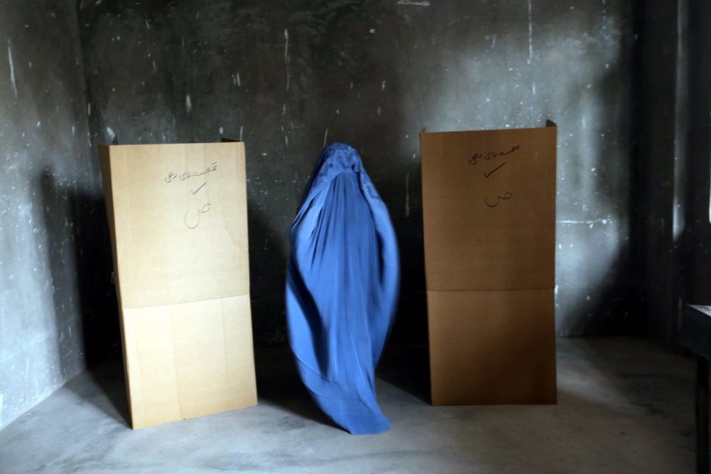 epaselect epa04255389 A burqa-clad Afghan woman casts her ballot at a polling station during Presidential elections run-off, in Herat, Afghanistan, 14 June 2014. Afghanistan holds a run-off presidential poll on 14 June after none of the eight candidates in the 05 April first round garnered the more than 50 percent required to win outright. Abdullah Abdullah, an ophthalmologist and former foreign minister, led the first round with 45 percent of the votes. His immediate rival, former finance minister Ashraf Ghani Ahmadzai, trailed with 31 percent.  EPA/JALIL REZAYEE