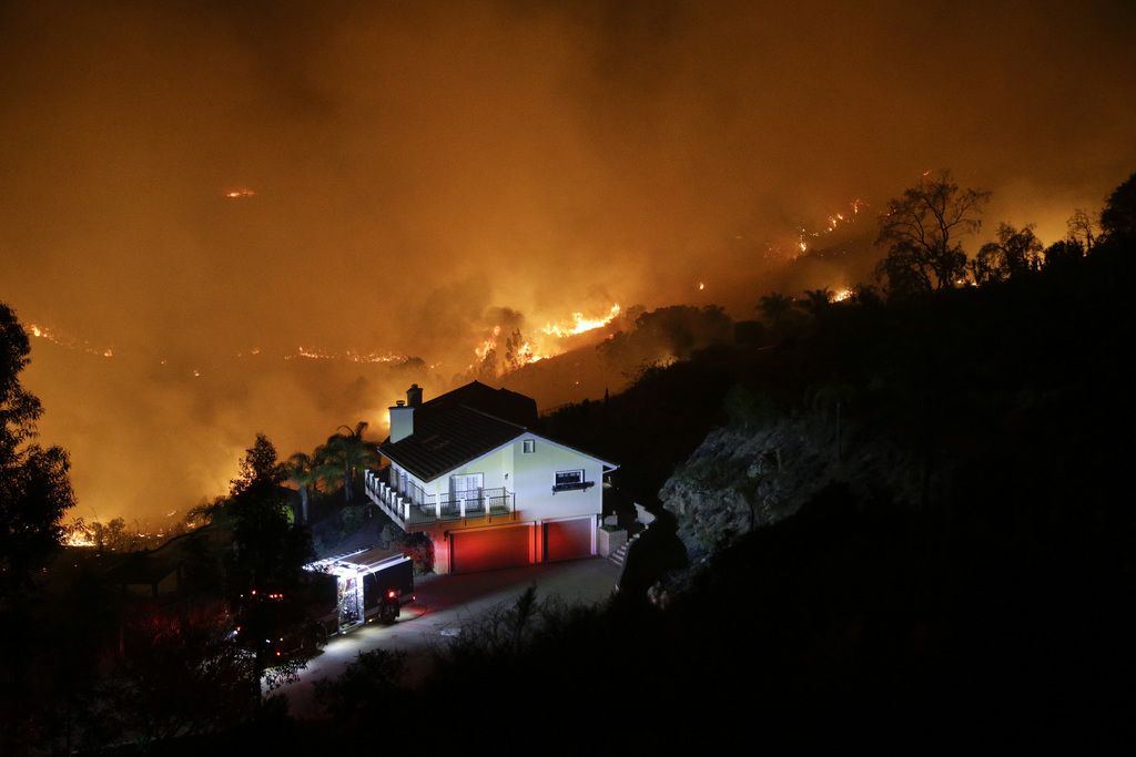 A wildfire burns near a home on Wednesday, May 14, 2014, in San Marcos, Calif. Flames engulfed suburban homes and shot up along canyon ridges in one of the worst of several blazes that broke out Wednesday in Southern California during a second day of a sweltering heat wave, taxing fire crews who fear the scattered fires mark only the beginning of a long wildfire season. (AP Photo)