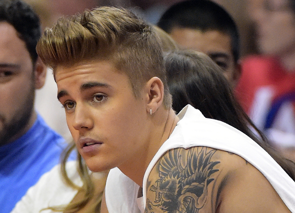 FILE - In this May 11, 2014, file photo, singer Justin Bieber watches the Los Angeles Clippers play the Oklahoma City Thunder during the second half of Game 4 of the Western Conference semifinal NBA basketball playoff series in Los Angeles. Canadian police say the pop star has been charged Tuesday, Sept. 2, 2014, with dangerous driving and assault after a collision between a minivan and an ATV led to a physical altercation in southwestern Ontario. Ontario Provincial Police say that the incident happened Friday afternoon, Aug. 29,  near Bieber's hometown of Stratford and that he was released on a promise to appear in court Sept. 29. (AP Photo/Mark J. Terrill, File)