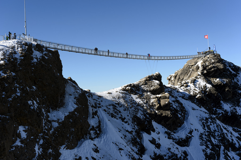 People walk on the bridge during the inauguration of the Peak Walk, the first and only suspension bridge to connect two mountain peaks, at the Glacier 3000 in Les Diablerets, Switzerland, Friday, 24 October, 2014. The Peak Walk connects the View Point peak with the main peak Scex Rouge (about 5 m higher). The 107 m long and 80 cm wide bridge offers a stunning view onto the Alps. (KEYSTONE/Laurent Gillieron)