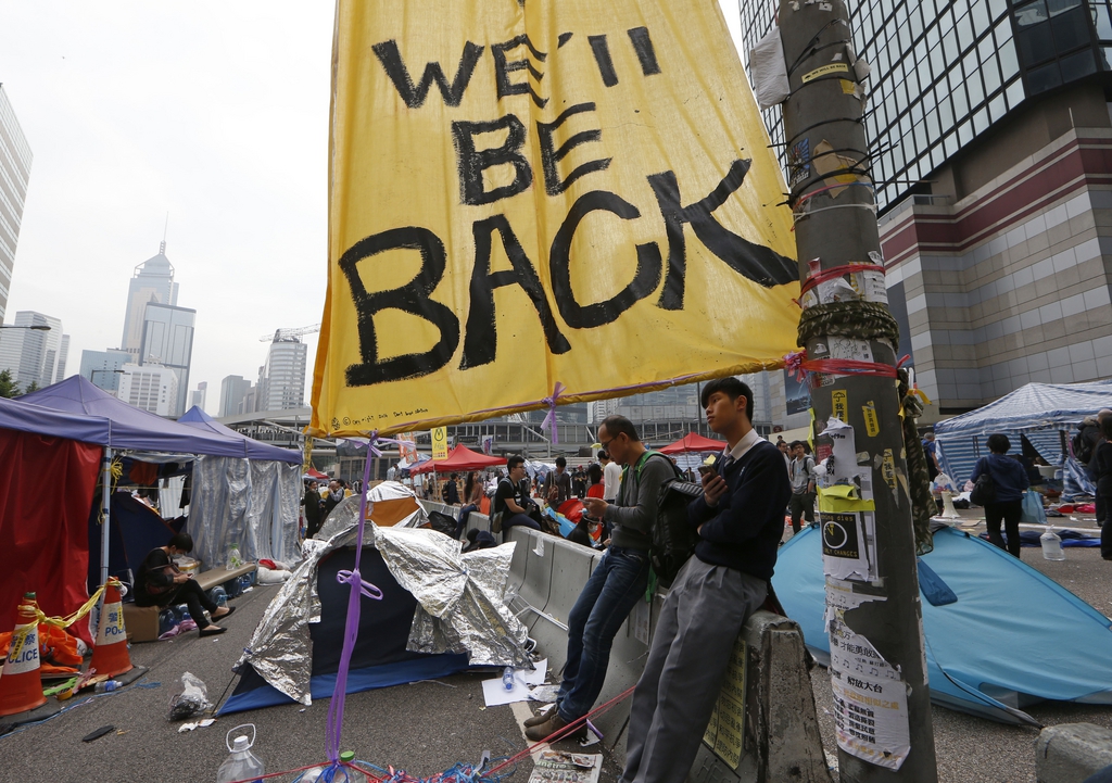 Protesters sit at an occupied area outside government headquarters in Hong Kong Thursday, Dec. 11, 2014. Hong Kong authorities started clearing barricades Thursday from a pro-democracy protest camp spread across a busy highway as part of a final push to retake streets occupied by activists for two and a half months. (AP Photo/Kin Cheung)