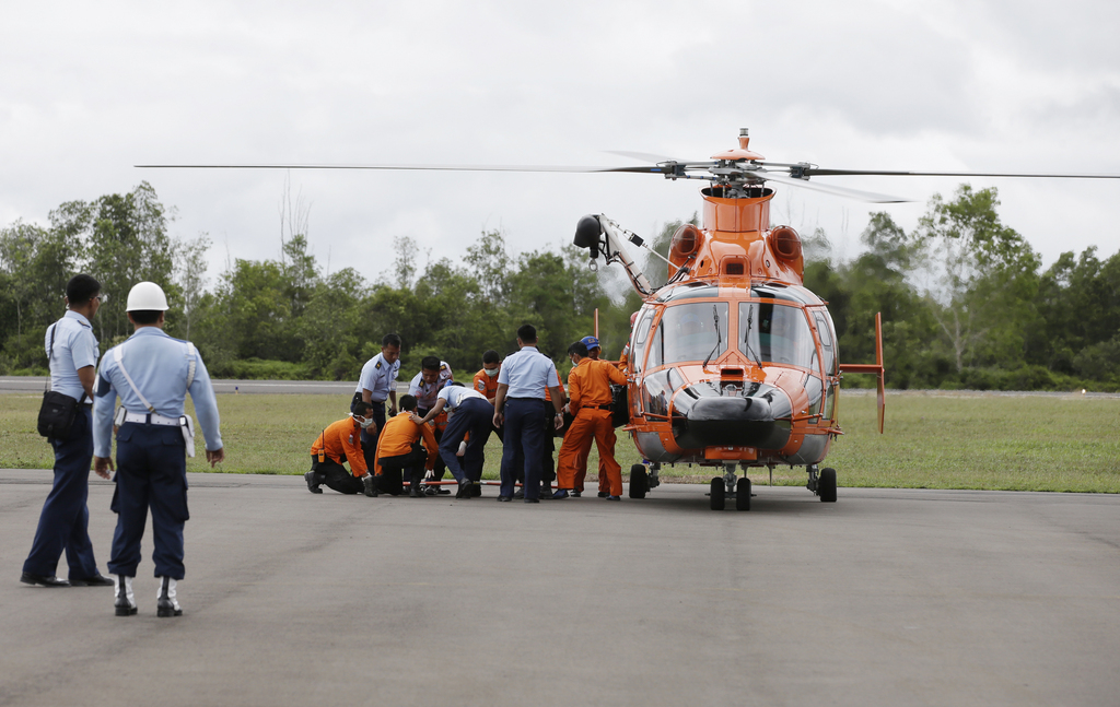 Officers of the National Search And Rescue Agency (BASARNAS) and Indonesian Air Force personnel unload a victim's body of the ill-fated AirAsia flight QZ 8501 from a helicopter  at the airport in Pangkalan Bun, Indonesia, Wednesday, Dec. 31, 2014. The first proof of the jet's fate emerged Tuesday in an area not far from where it dropped off radar screens on Sunday morning. Searchers found  bodies and debris that included a life jacket, an emergency exit door and a suitcase about 10 miles from the plane's last known coordinates. (AP Photo/Achmad Ibrahim)