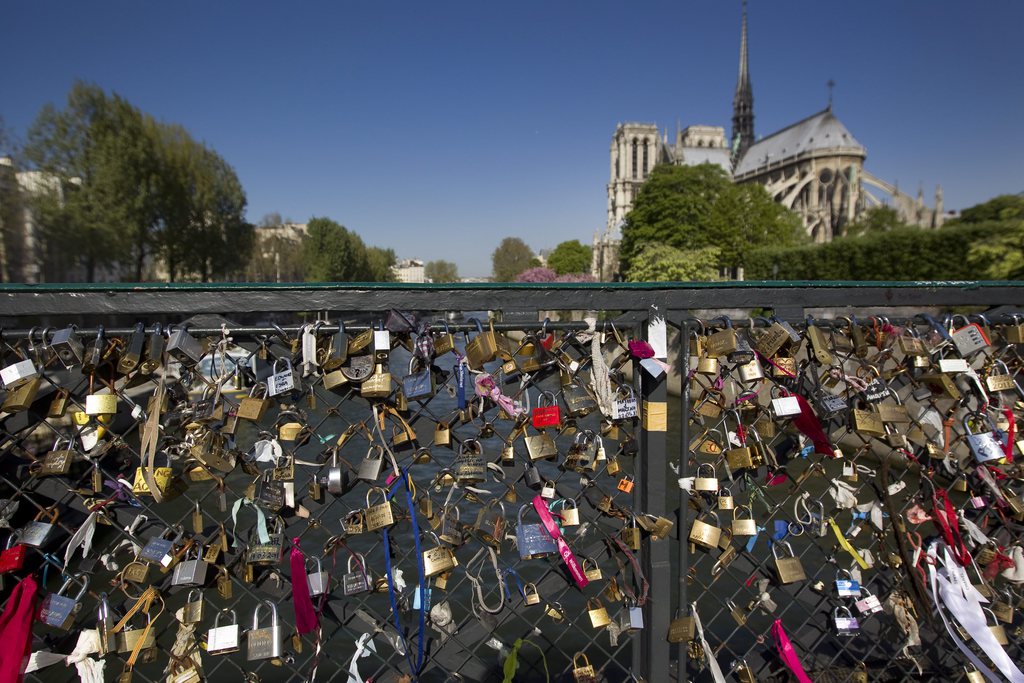 epa02673724 Padlocks placed by lovers adorn the railings of the Pont de l'Archeveque bridge on the Seine river, overlooking Notre-Dame Cathedral, in Paris, France, 07 April 2011. Tourists and Parisians alike lock personalized love-padlocks, or 'cadenas d'amour' on the bridge's railings and throw the keys into the Seine River. The padlock-clad railings have now become a popular attraction in the city.  EPA/IAN LANGSDON