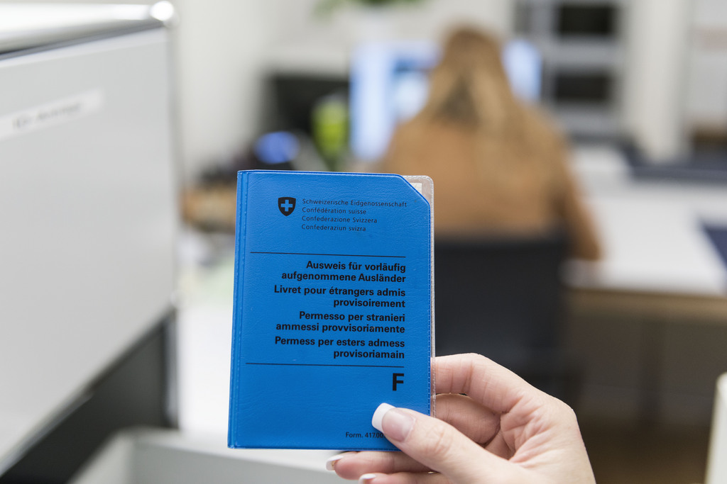 An employee of the residents' registration office in Schaffhausen, Switzerland, holds a foreign national identity card, pictured on October 7, 2014. (KEYSTONE/Christian Beutler)