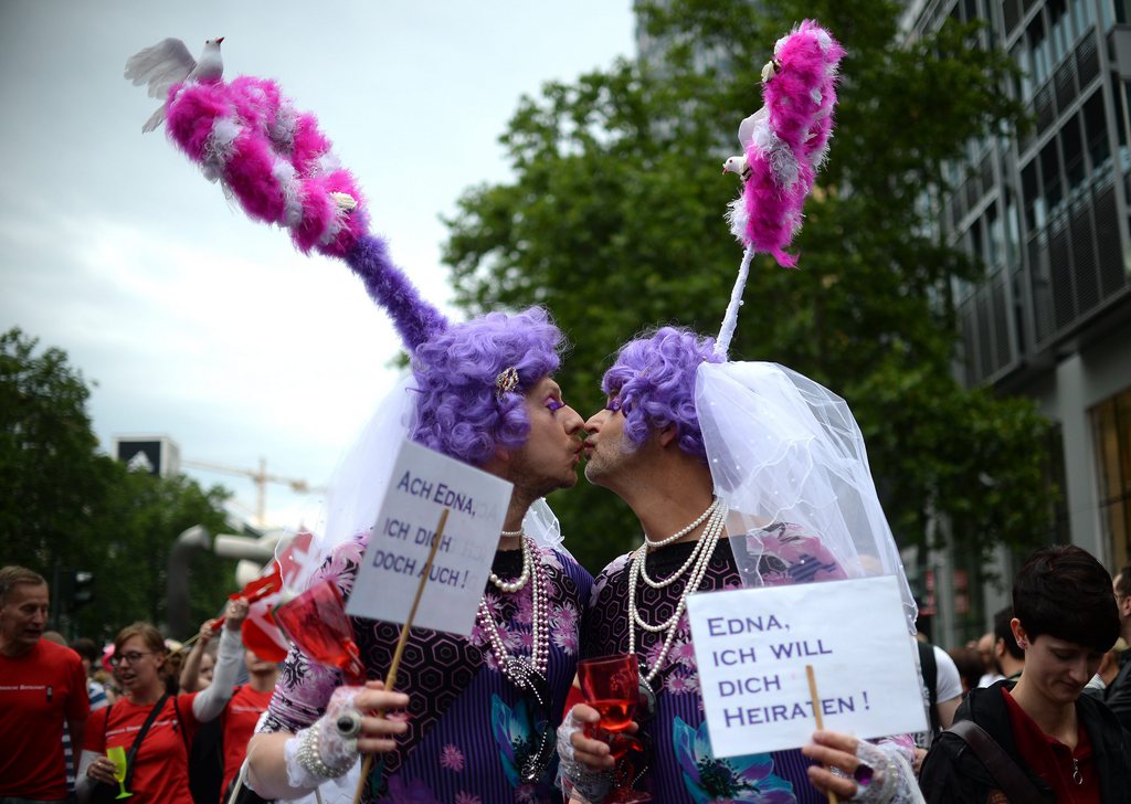 epa04821281 Two participants kiss at Christopher Street Day (CSD) in Berlin, Germany, 27 June 2015. Under the slogan 'Wir sind alle anders. Wir sind alle gleich' (lit. We are all different. We are all equal), were participants parading through the city. The focus of this year's parade is extending the right to marry to same-sex couples. Sign at right reads: Edna, I want to marry you! Sign left reads: Oh Edna, I want it too!  EPA/BRITTA PEDERSEN