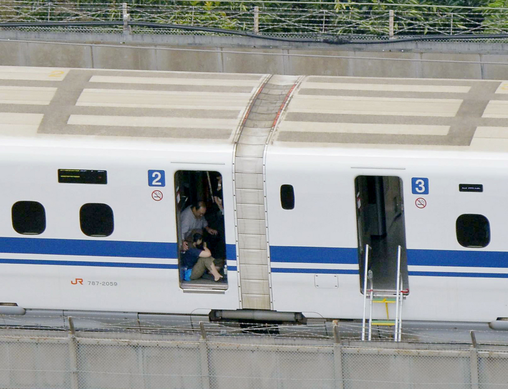 A passenger crouches inside a train car of the Shinkansen bullet train which made an emergency stop in Odawara, near Tokyo Tuesday, June 30, 2015. A passenger poured oil and set himself or herself on fire, causing fire and smoke in the car. (Kyodo News via AP Photo) JAPAN OUT, MANDATORY CREDIT