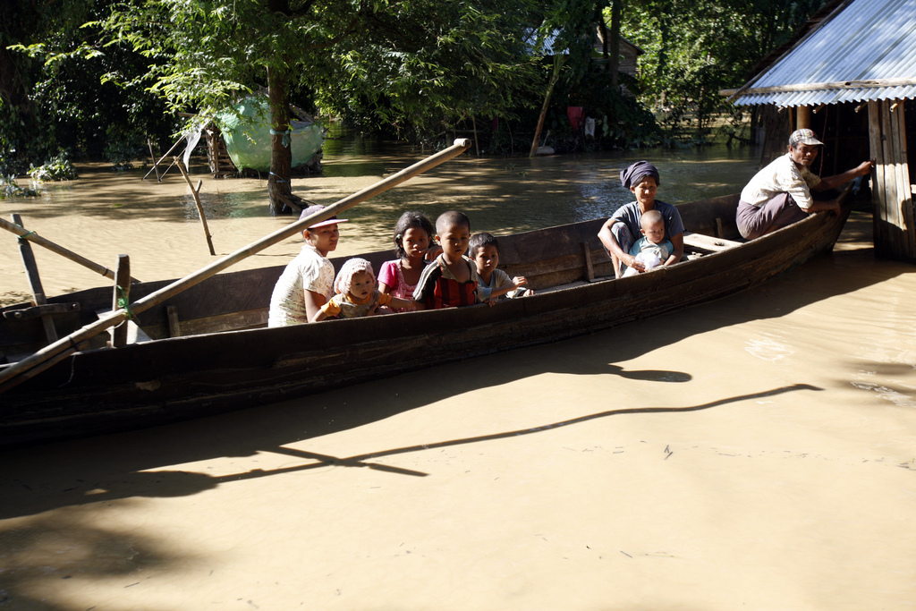 In this Sunday, Aug. 9, 2015 photo, flood-affected people sitting on a boat wait to receive foods from a private donor in Hinthada township, Ayeyarwaddy delta, Myanmar. The number of people affected by flooding across Myanmar was approaching 1 million on Sunday, with waters in the low-lying southwestern delta inundating homes and forcing villagers into temporary shelters, the government said. (AP Photo/Khin Maung Win)