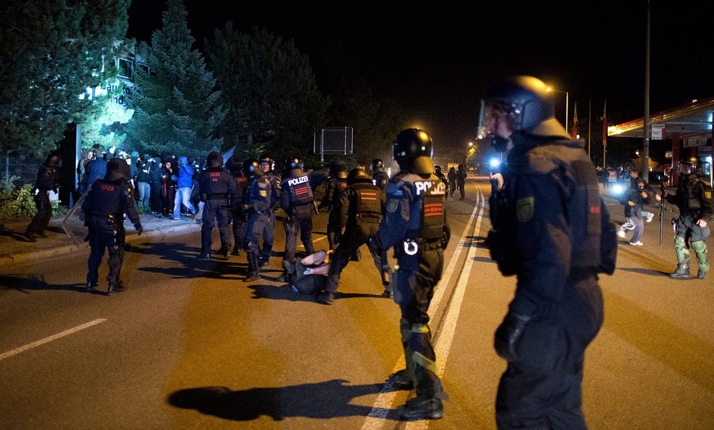 epa04895384 Riot police intercepts hooded people trying to enter the area near the security zone around a former hardware store that has been turned into an emergency shelter for refugees in Heidenau, Germany, 23 August 2015. The eastern German town of Heidenau was bracing for a possible third night of violence centred around a recently opened home for asylum seekers, a night after two policemen were injured in the latest stand-off. Police used tear gas to disperse right-wing extremists who blocked a road leading to a hardware store that had been retrofitted to serve as a temporary housing facility.  EPA/ARNO BURGI  EPA/ARNO BURGI  EPA/ARNO BURGI