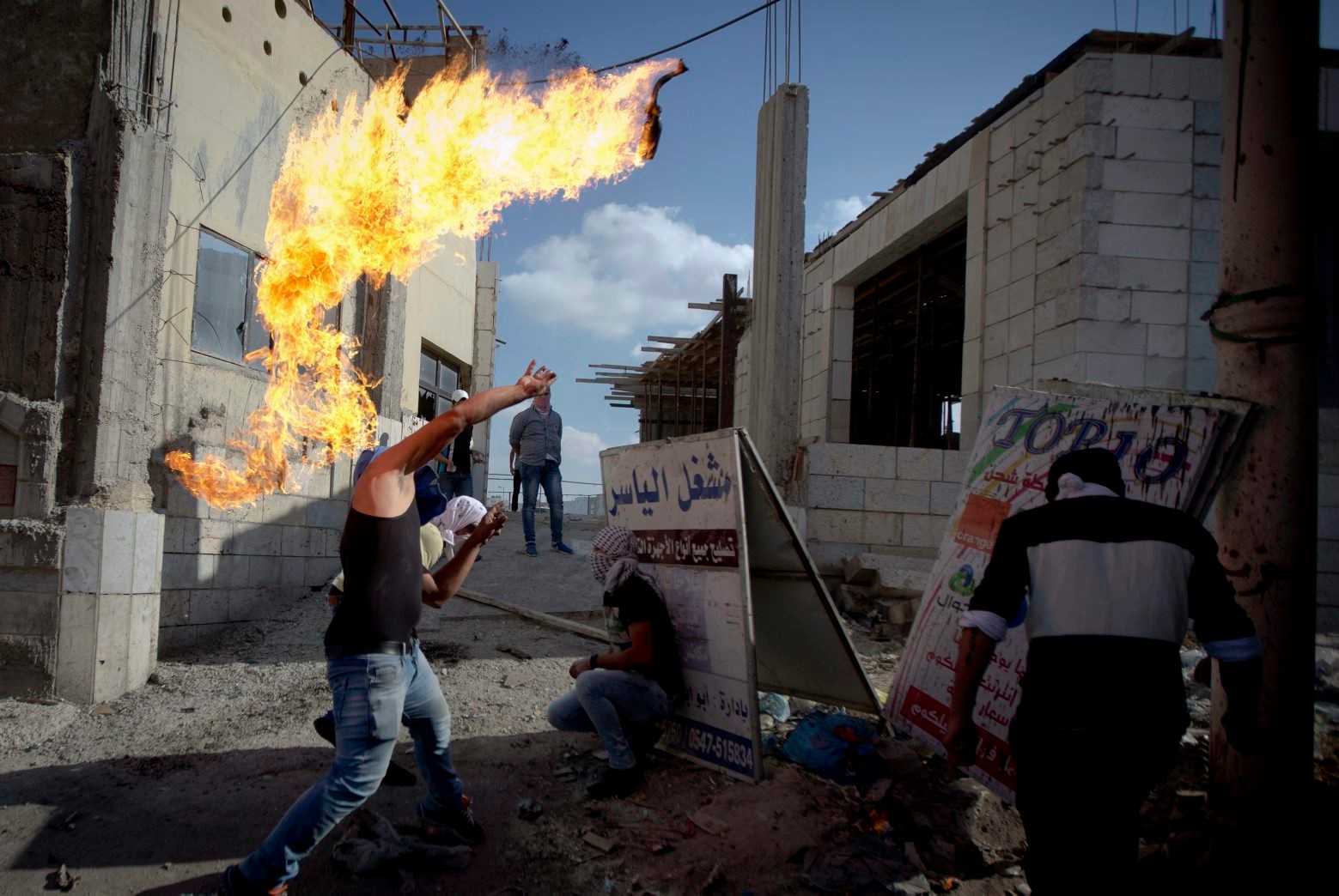 A Palestinian throws a Molotov cocktail during clashes with Israeli troops at Qalandia checkpoint between Jerusalem and the West Bank city of Ramallah, Tuesday, Oct. 6, 2015. A new generation of angry, disillusioned Palestinians is driving the current wave of clashes with Israeli forces: They are too young to remember the hardships of life during Israel's clampdown on the last major uprising, and after years of nationalist Israeli governments many have lost faith in statehood through negotiations and believe Israel only understands force. (AP Photo/Majdi Mohammed) Mideast Palestinians Young and Angry