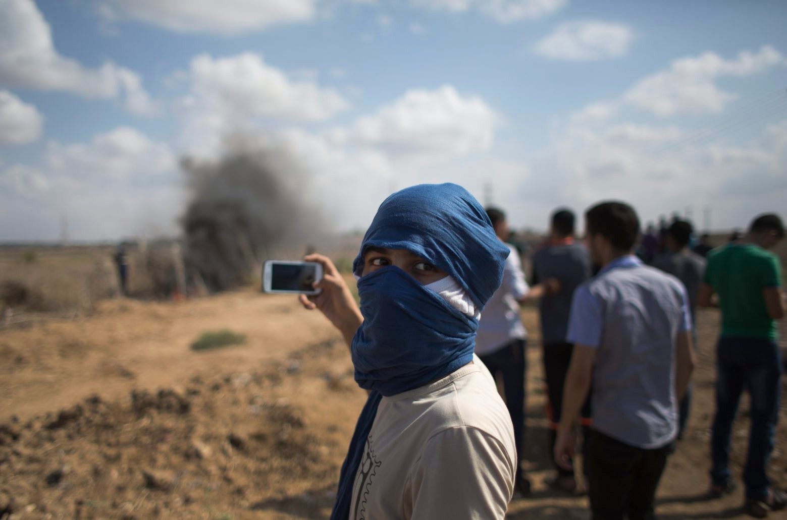 A Palestinian protester films with his mobile phone, during clashes with Israeli soldiers on the Israeli border Eastern Gaza City, Friday, Oct. 9, 2015. At least four attacks ó three by Palestinians and one by an Israeli ó as well as deadly clashes along the Gaza border threatened to escalate tensions throughout the country on Friday as Israel struggled to control spiraling violence. (AP Photo/Khalil Hamra) APTOPIX Mideast Israeli Palestinians