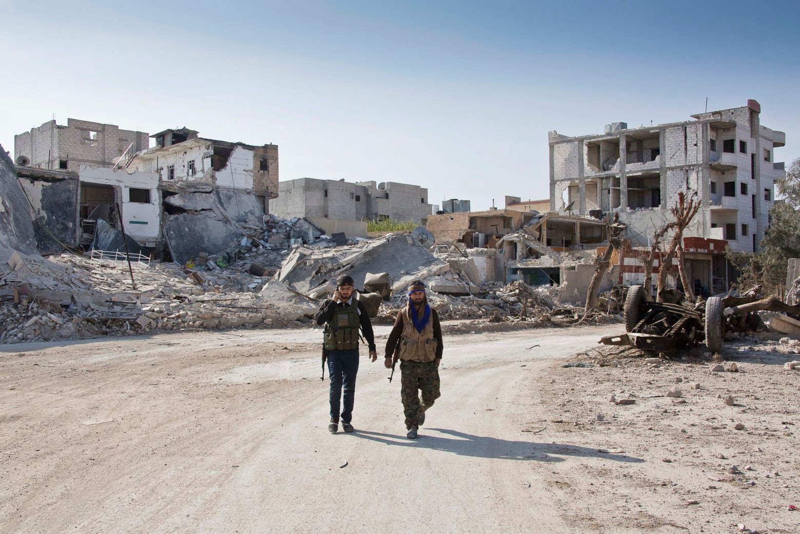 FILE - In this Nov. 19, 2014 file photo, Kurdish People's Protection Units (YPG) soldiers walk near the town entrance circle heading to their strongholds in Kobani, Syria. Amnesty International said the U.S.-backed Kurdish administration in northern Syria has deliberately displaced thousands of mainly Arab citizens and demolished homes. The report released Tuesday, Oct. 13, 2015, said that the abuses, which amount to war crimes, were often carried out in retaliation for residents' perceived sympathies for or ties to the Islamic State group or other militants. (AP Photo/Jake Simkin, File) Mideast Syria Displaced By Kurds