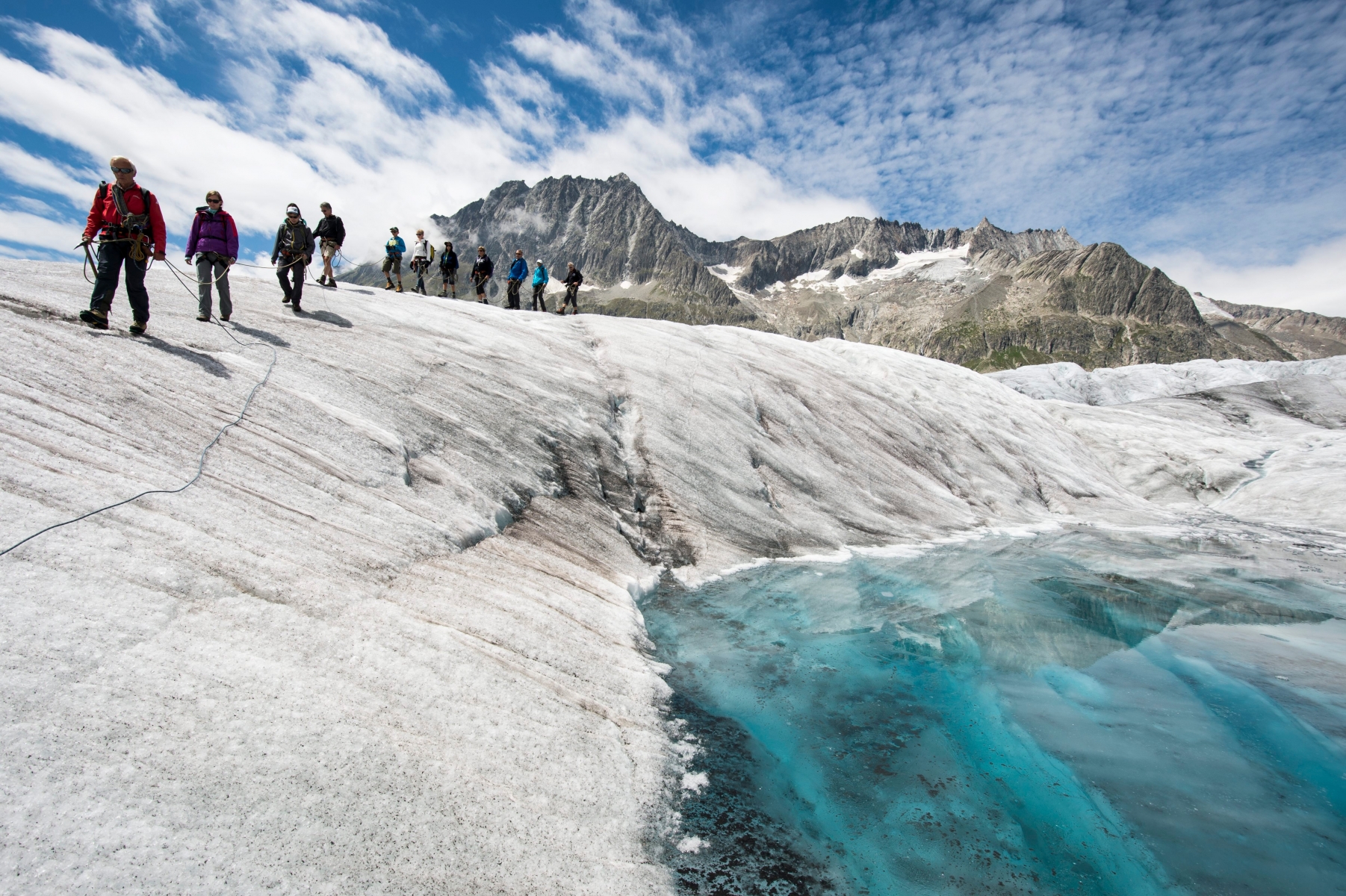 Tourists passing by a small lake during a guided tour on the Aletsch glacier, in Fiesch, Switzerland, Tuesday, July 28, 2015. With 23 kilometers is the Aletsch glacier the longest glacier of Europe and belongs to the UNESCO world heritage sites. (KEYSTONE/Dominic Steinmann) SCHWEIZ ALETSCH GLACIER GUIDED TOUR