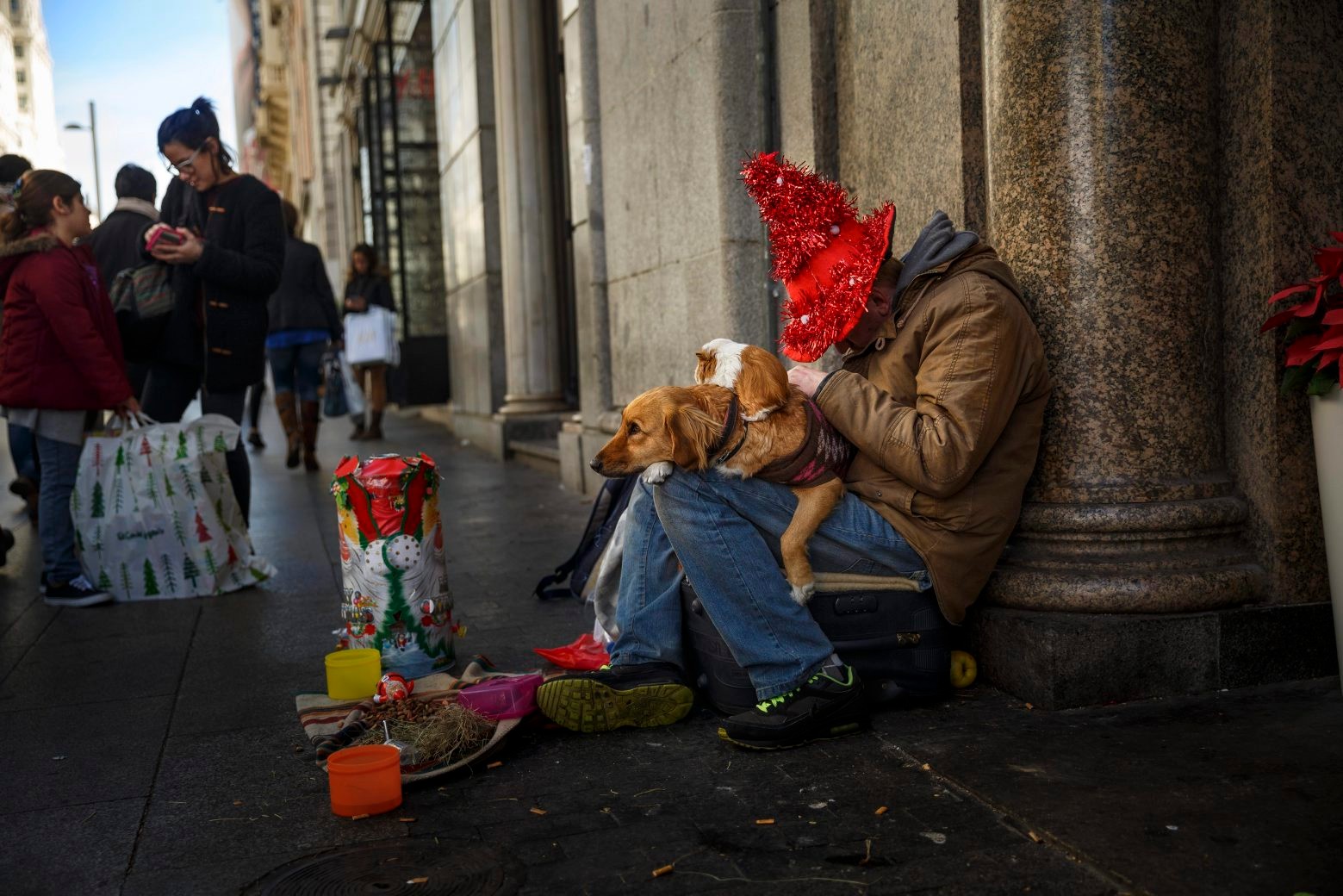 A man sleeps while begging with a dog and a Guinea pig on his knees in central Madrid, Wednesday, Dec. 9, 2015. (AP Photo/Daniel Ochoa de Olza) Spain Daily Life