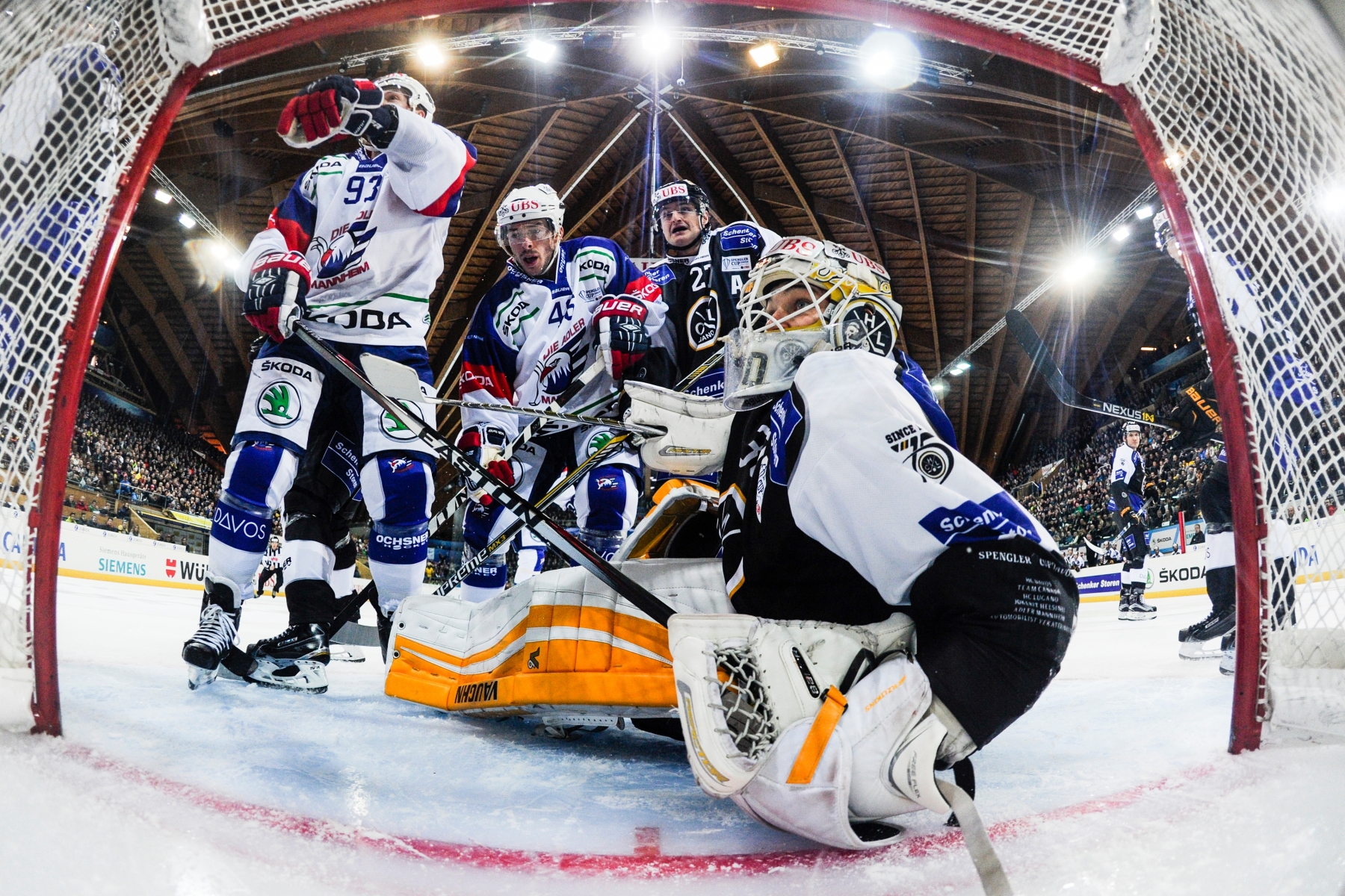 Lugano's goalkeeper Elvis Merzlikins, right, fights for the puck with Mannheim's Brent Raedeke and Jon Rheualt, from left, during the game between Switzerland's HC Lugano and Germany's Adler Mannheim, at the 89th Spengler Cup ice hockey tournament in Davos, Switzerland, on Saturday, December 26, 2015. (KEYSTONE/Gian Ehrenzeller) EISHOCKEY SPENGLER CUP 2015 LUGANO MANNHEIM
