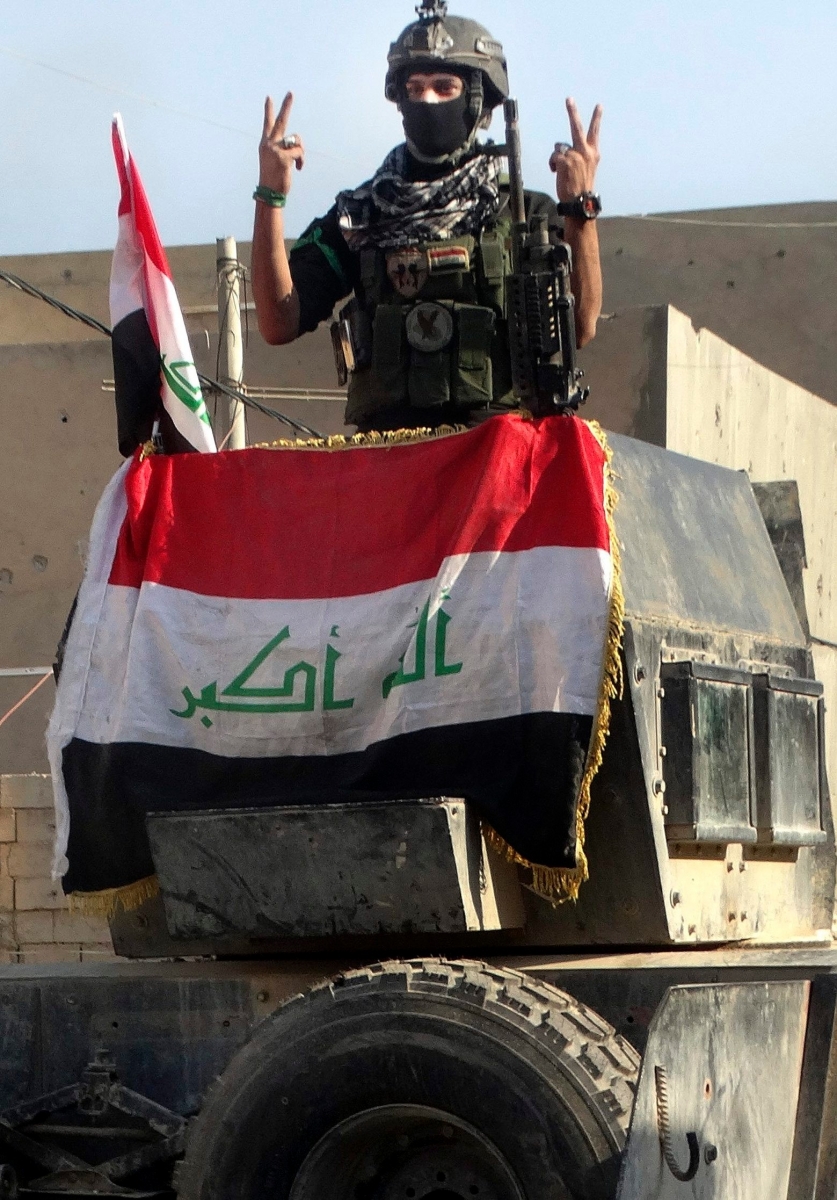 An Iraqi soldier flashes the victory sign after entering the government complex in central Ramadi, 70 miles (115 kilometers) west of Baghdad, Iraq, Monday, Dec. 28, 2015. Iraqi military forces on Monday retook a strategic government complex in the city of Ramadi from Islamic State militants who have occupied the city since May. (AP Photo/Osama Sami) Mideast Iraq Islamic State