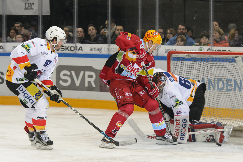 Le top-scorer lausannois Harri Pesonen (en rouge) lutte pour le puck avec le Biennois Mathias Joggi et son gardien Simon Rytz.