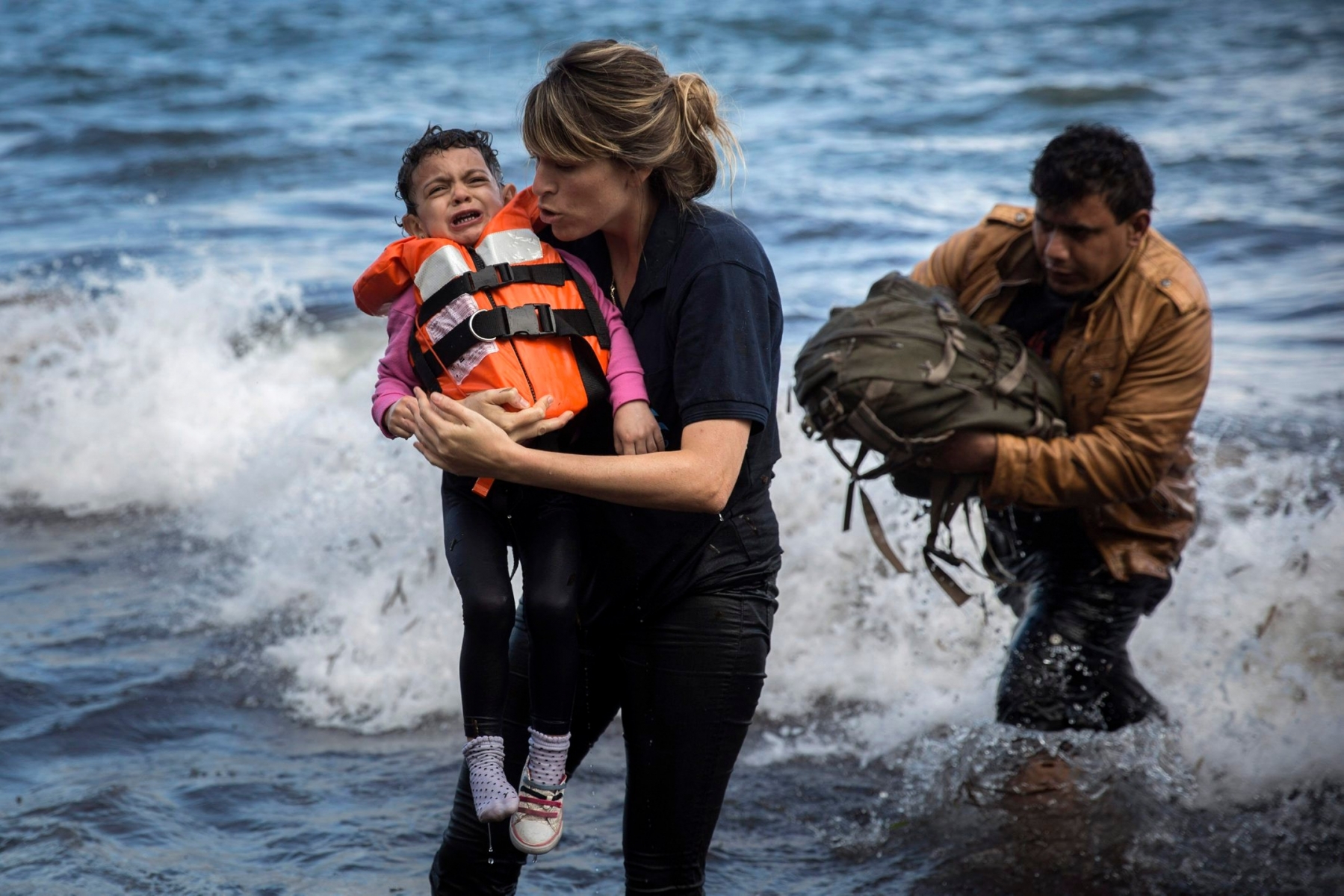 A volunteer holds a Syrian child after arriving with a group of migrants on a dinghy from the Turkish coast to the northeastern Greek island of Lesbos, on Wednesday, Sept. 30, 2015.  The International Organization for Migration says a record number of people have crossed the Mediterranean into Europe this year, now topping a half a million, with some 388,000 entering via Greece. (AP Photo/Santi Palacios) APTOPIX Greece Migrants