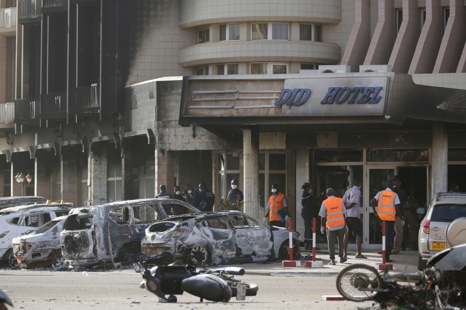 Rescue workers inspect damaged cars at the entrance of the Splendid Hotel in Ouagadougou, Burkina Faso, Saturday, Jan. 16, 2016. The overnight seizure of a luxury hotel in Burkina Faso's capital by al-Qaida-linked extremists ended Saturday when Burkina Faso and French security forces killed four jihadist attackers and freed more than 126 people, the West African nation's president said. (AP Photo/Sunday Alamba) Burkina Faso Hotel Attack
