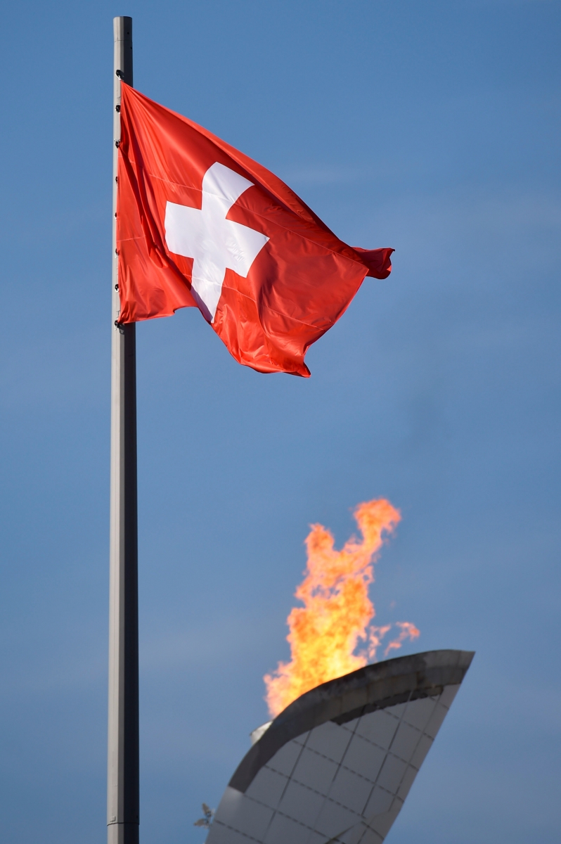 The Swiss flag is seen in front of the Olympic Flame on the top of the Olympic cauldron in the Olympic Park at the XXII Winter Olympics 2014 Sochi, in Sochi, Russia, on Saturday, February 15, 2014. (KEYSTONE/Laurent Gillieron)d OLYMPIA SOTSCHI 2014