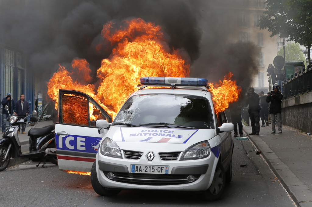 La voiture de police a été incendiée au milieu d'une rue par un groupe de jeunes casseurs.