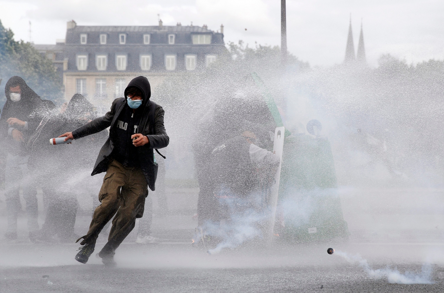 epa05364375 A protester runs from the scene as others duck behind a toppled garbage container as they protect themselves from water cannons used by riot police to disperse the crowd during a national demonstration and strike against the Labor Law reform in Paris, France, 14 June 2016. Labor unions demonstrated during a national strike across France to protest against about employment law reforms in the so-called El Khomri bill.  EPA/YOAN VALAT FRANCE LABOUR PROTEST