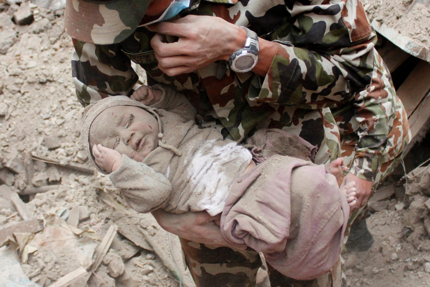 In this Sunday, April 26, 2015, photo taken by Amul Thapa and provided by KathmanduToday.com, four-month-old baby boy Sonit Awal is held up by Nepalese Army soldiers after being rescued from the rubble of his house in Bhaktapur, Nepal, after Saturday's 7.8-magnitude earthquake shook the densely populated Kathmandu valley.  Thapa says that when he saw the baby alive after 20 hours of rescue efforts ÏÖ all my sorrow went. Everyone was clapping. It gave me energy and made me smile in spite of lots of pain hidden inside me." (Amul Thapa/KathmanduToday.com via AP)Sonis Awal âgé de 4 mois, a survécu après avoir passé 22 heures sous les décombres. Nepal Earthquake Baby Rescue