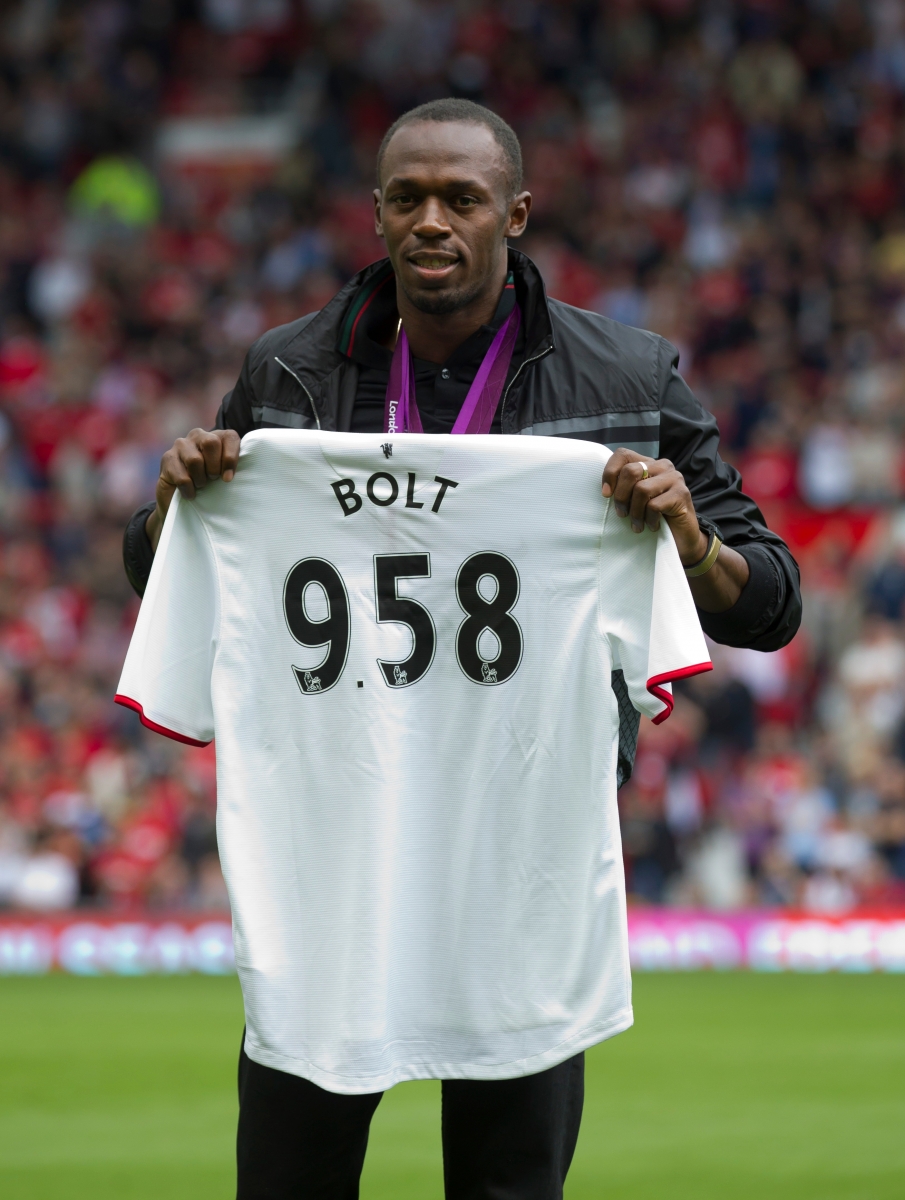Sprinter Usain Bolt poses for pictures with a shirt showing the World Record time for the 100 metres sprint, before Manchester United's English Premier League soccer match against Fulham at Old Trafford Stadium, Manchester, England, Saturday, Aug. 25, 2012. (AP Photo/Jon Super)bolt Britain Soccer Premier League