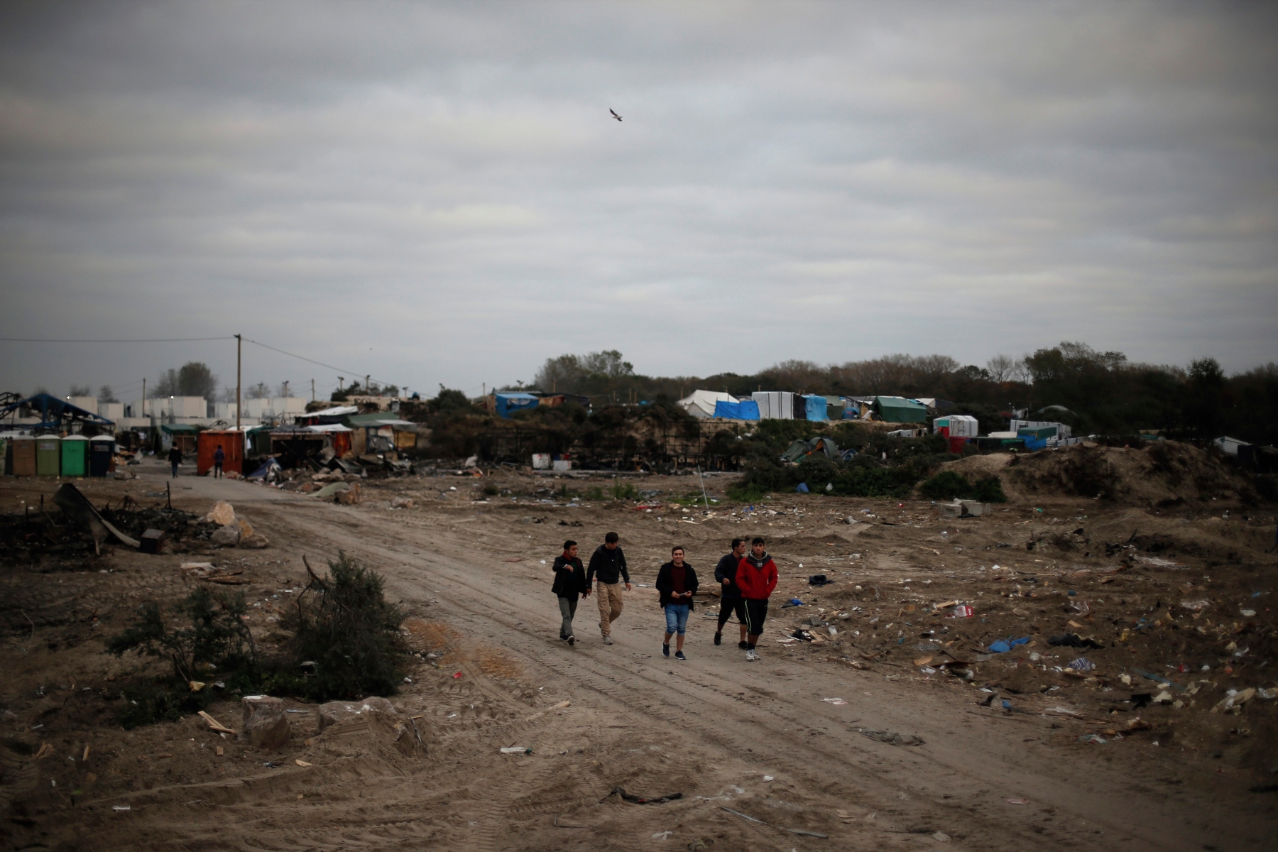 Migrants walk in the makeshift migrant camp known as "the jungle", near Calais, northern France, Friday, Oct. 28, 2016. Thousands of migrants dispersed this week from the now-torched camp they had called home in Calais, and are now struggling to adapt to unfamiliar surroundings in various towns and villages throughout France. (AP Photo/Thibault Camus) France Migrants