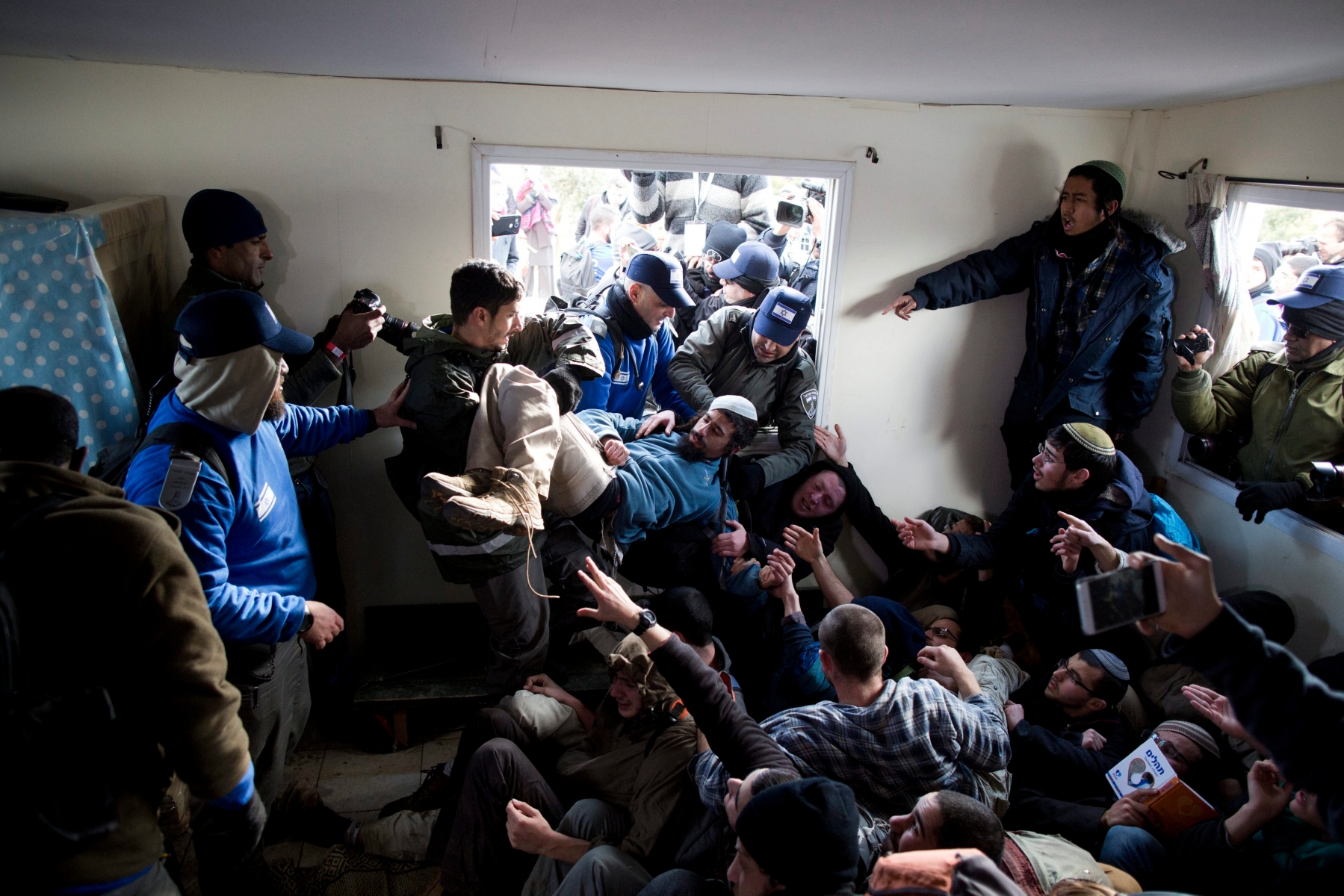 epa05764800 Israeli security forces try to arrest settlers who hold each other in a house during the evacuation of the illegal Jewish settlement of Amona, in the West Bank, 01 February 2017. Israeli police have deployed 3,000 policemen around the settlement for a planned eviction ordered by the Israeli Supreme Court.  EPA/ABIR SULTAN MIDEAST ISRAEL SETTLERS AMONA