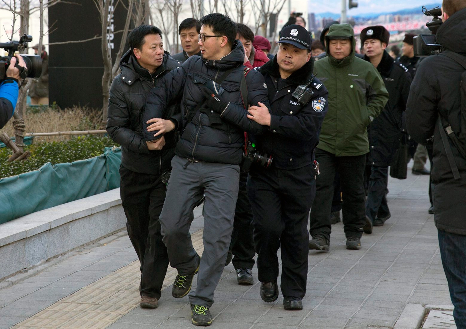 In this Sunday, Jan. 26, 2014 photo, Chinese policemen manhandle a foreign photographer, center, as he photographs Zhang Qingfang, lawyer of legal scholar and founder of the New Citizens movement Xu Zhiyong, speaking to the media near the No. 1 Intermediate People's Court, where Xu appeared for his verdict in Beijing. The government is intensifying efforts to control foreign media coverage of China, blocking websites, harassing reporters trying to cover trials of activists in Beijing and thwarting efforts by The New York Times to station new journalists on the mainland. (AP Photo/Andy Wong) China Journalists Under Pressure