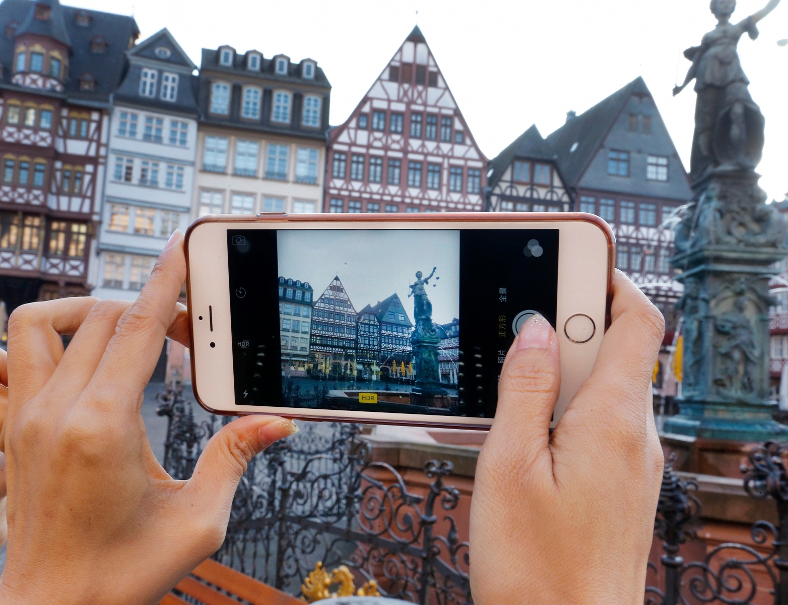 A Chinese tourist takes a picture of the half-timber houses at the Roemerberg square in Frankfurt, Germany, Friday, Oct. 14, 2016. (AP Photo/Michael Probst) Germany Daily Life