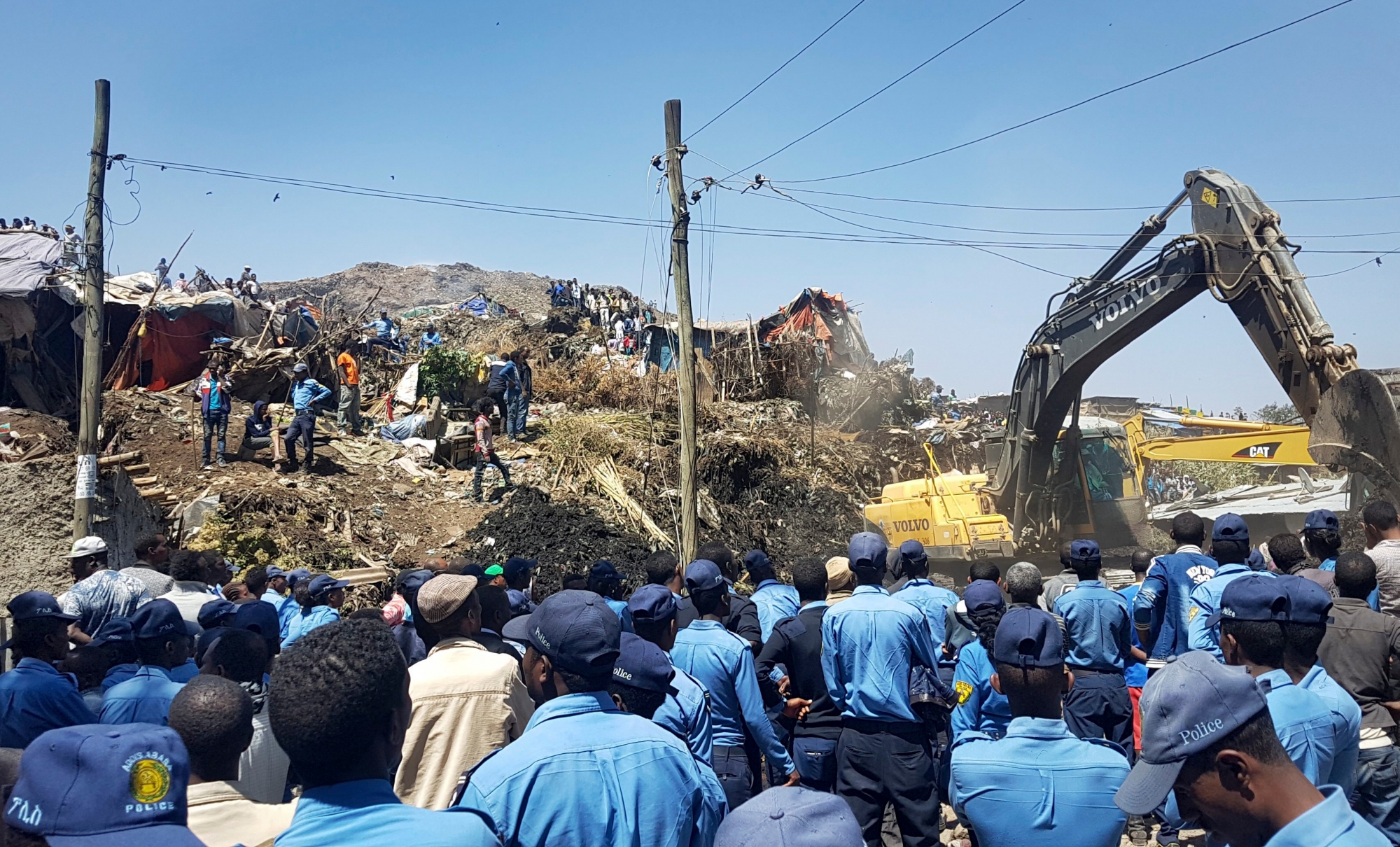 Police officers secure the perimeter at the scene of a garbage landslide, as excavators aid rescue efforts, on the outskirts of the capital Addis Ababa, Ethiopia Sunday, March 12, 2017. Officials and residents say more than a dozen people have been killed in a landslide at a massive garbage dump on the outskirts of Ethiopia's capital, and several dozen people are missing. (AP Photo/Elias Meseret) APTOPIX Ethiopia Deadly Landslide