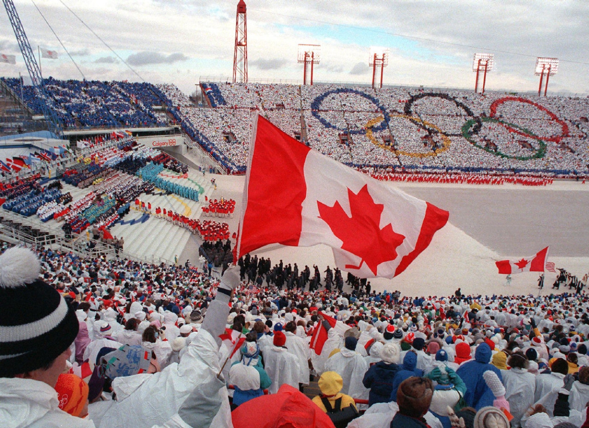 Fans cheer and wave flags as the Canadian delegation (lower right) parades during the opening ceremony of the XVth Winter Olympic Games 13 February 1988 in Calgary.  AFP PHOTO/JONATHAN UTZ (Photo credit should read JONATHAN UTZ/AFP/Getty Images)calgary Calgary games opening ceremony